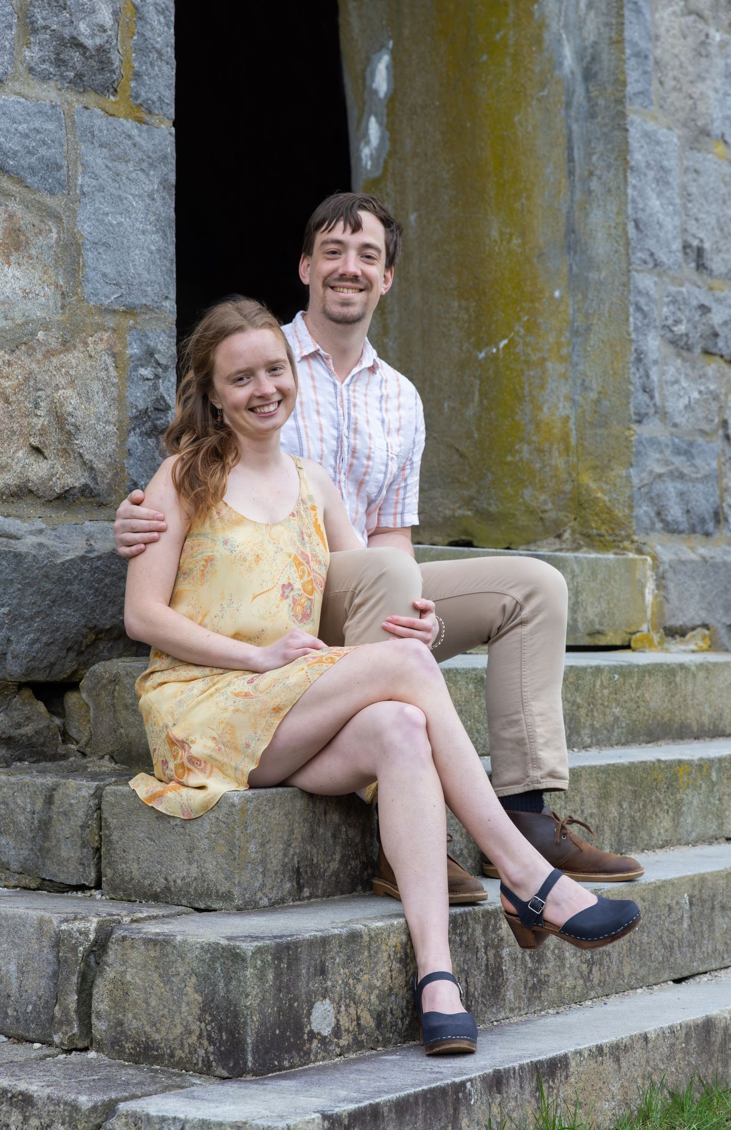 A couple sits together on stone steps against a weathered wall in a series of casual outdoor photos.