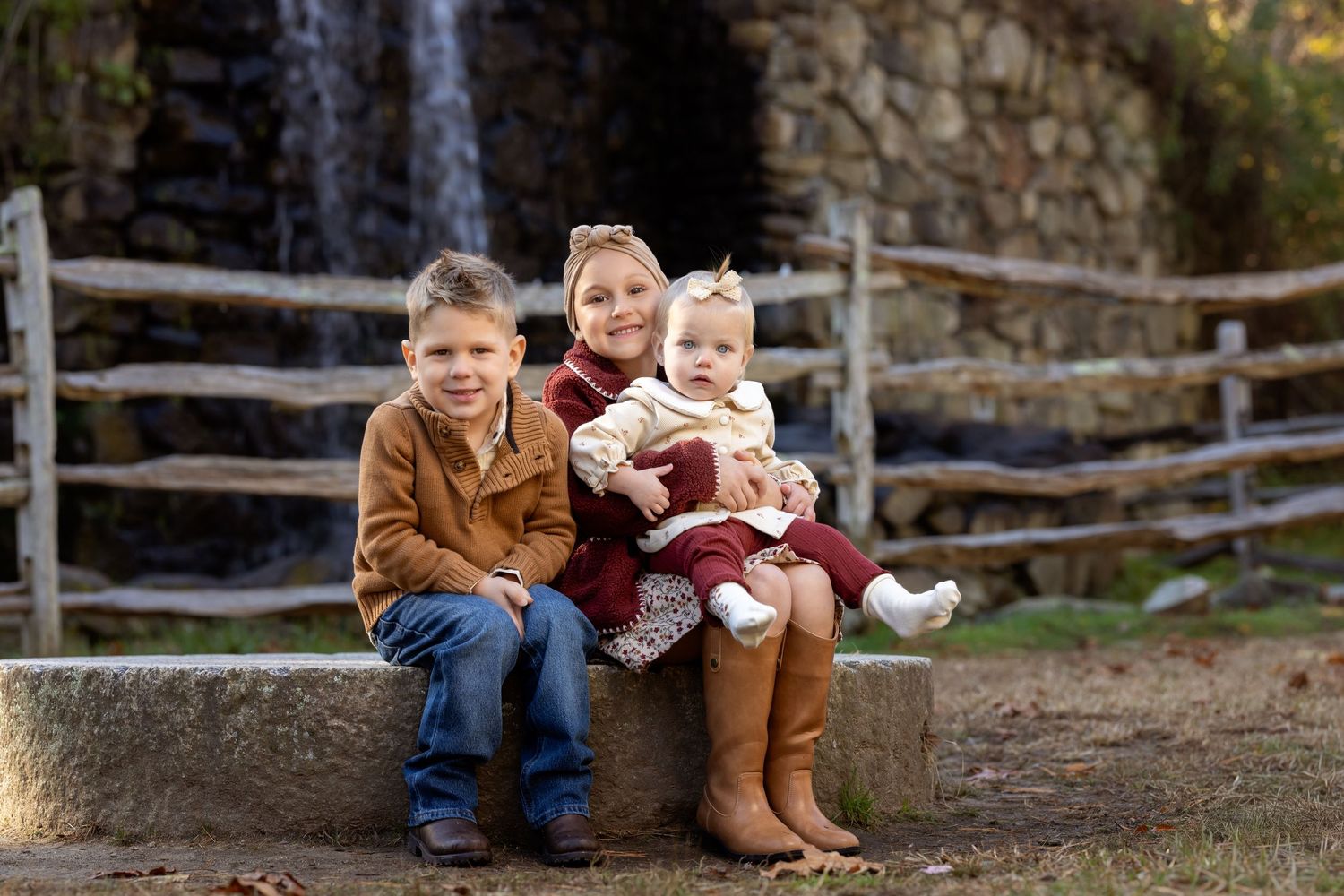 A group of people sitting on wooden steps outdoors in autumn clothing for a casual photo session.
