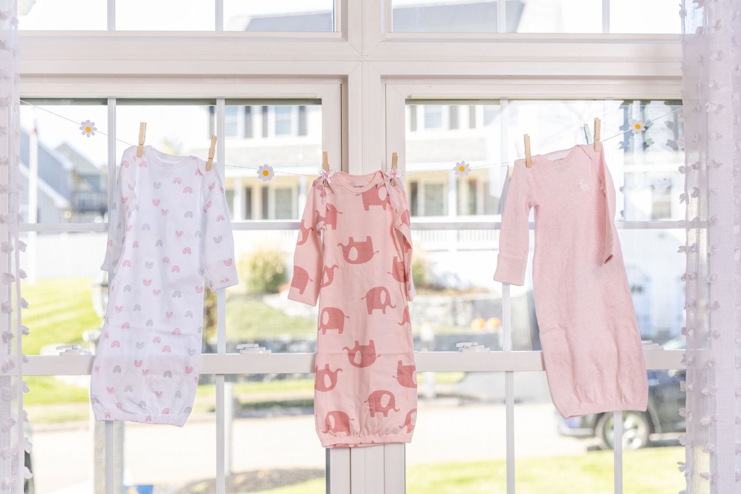 Colorful baby clothes and linens hanging to dry on a clothesline outside on a sunny day.