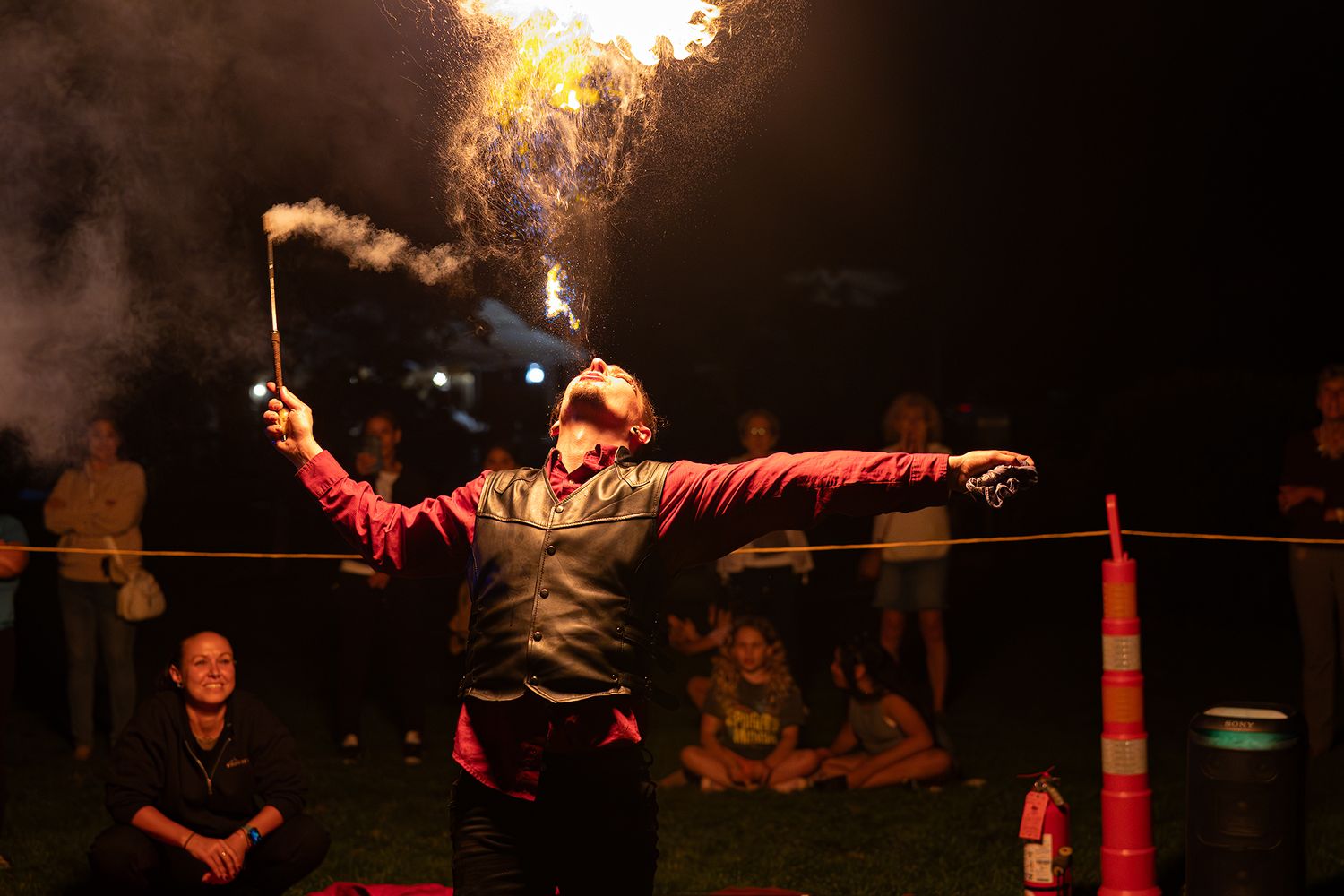 Fire performers create a dramatic display with flaming torches and staffs during an outdoor nighttime show.