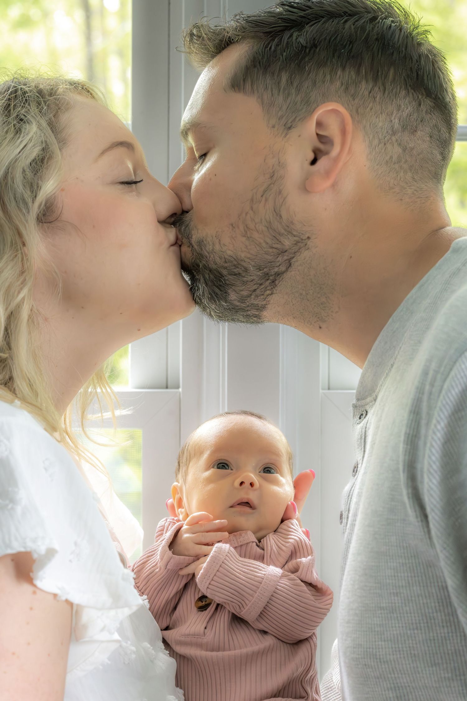 A series of four intimate photos showing tender family moments with a baby in pink clothing.