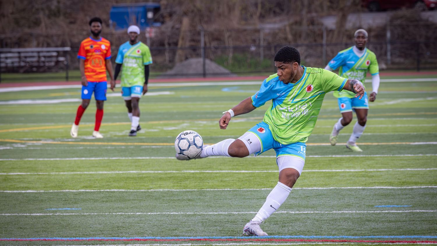 Soccer players in neon yellow and white uniforms compete for the ball on an artificial turf field during a match.