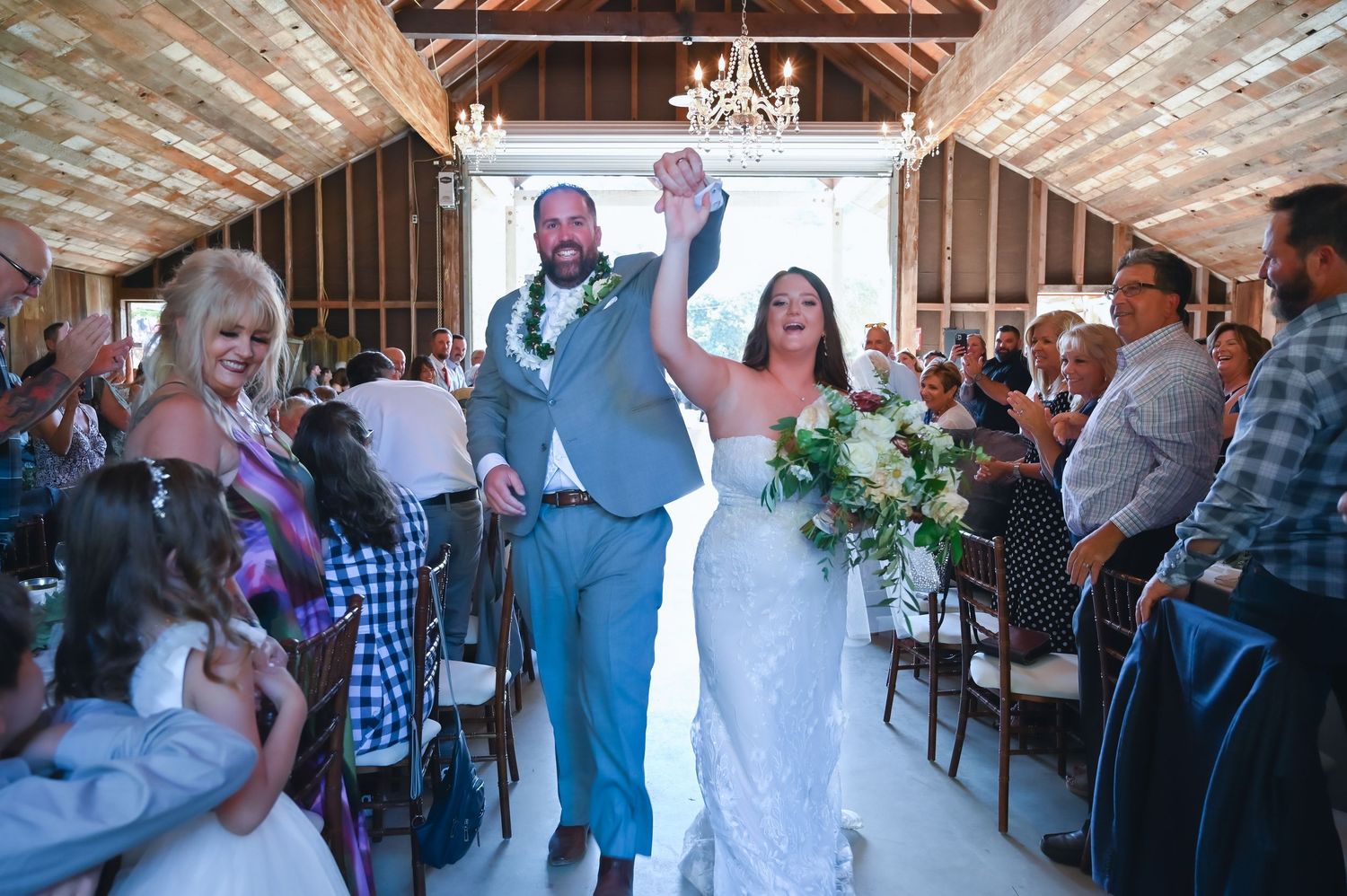 Wedding reception in a rustic barn venue with exposed beams and chandeliers.