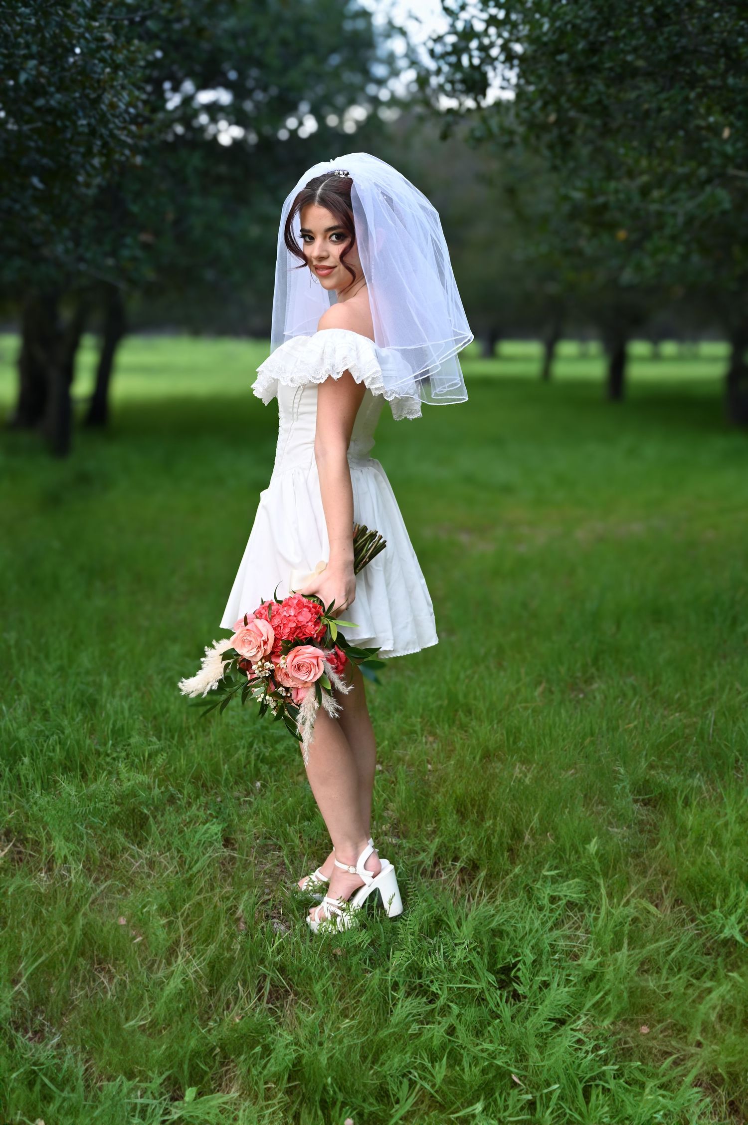 Creative wedding photography showing bride's dress and floral details against lush green backdrop.