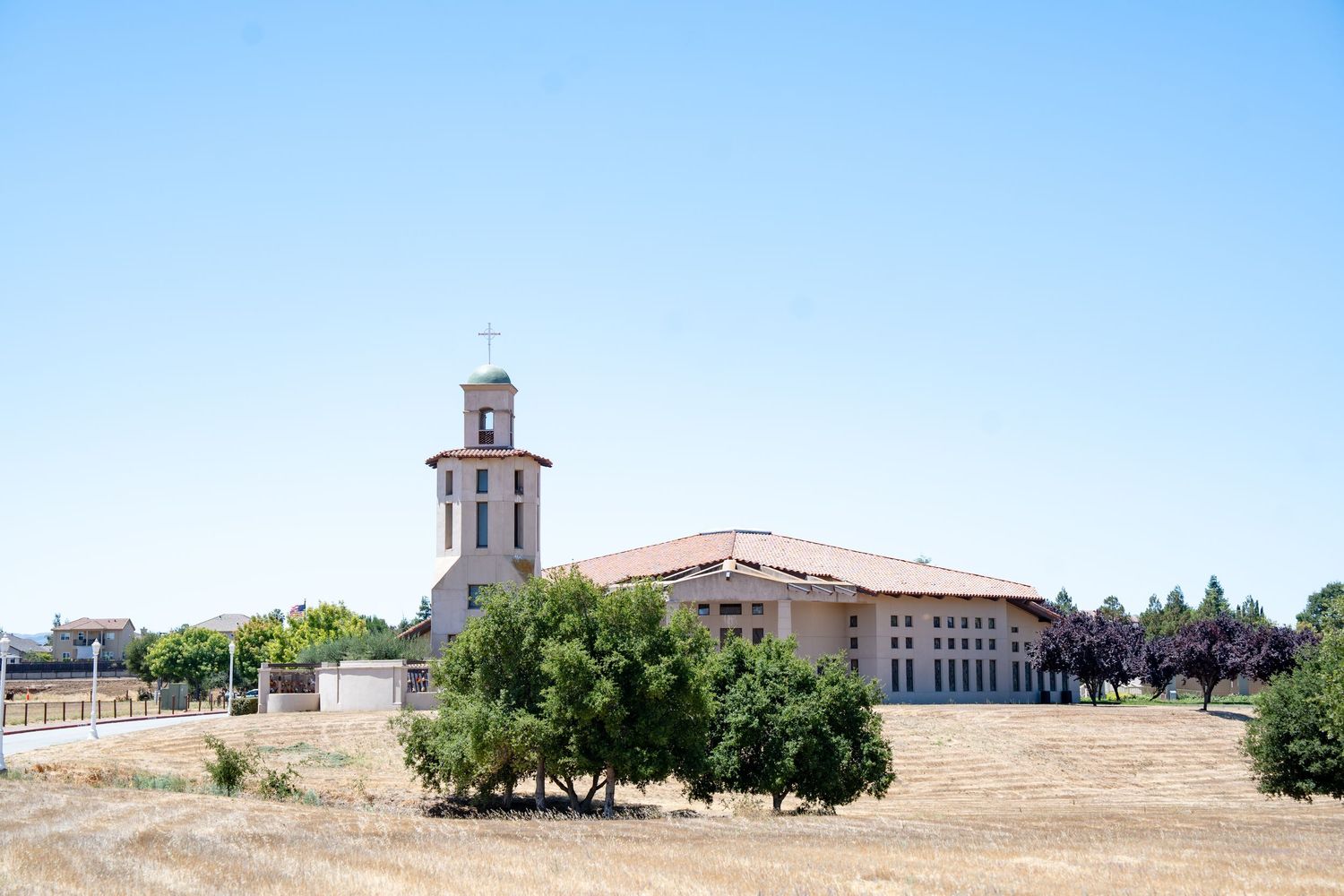 Scenic view of a Spanish mission style church building with bell tower against blue sky.