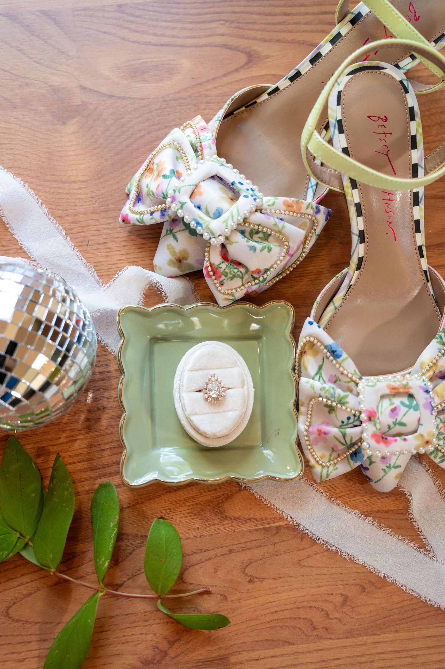 Wedding accessories including sparkly shoes and ring box arranged on green tray.