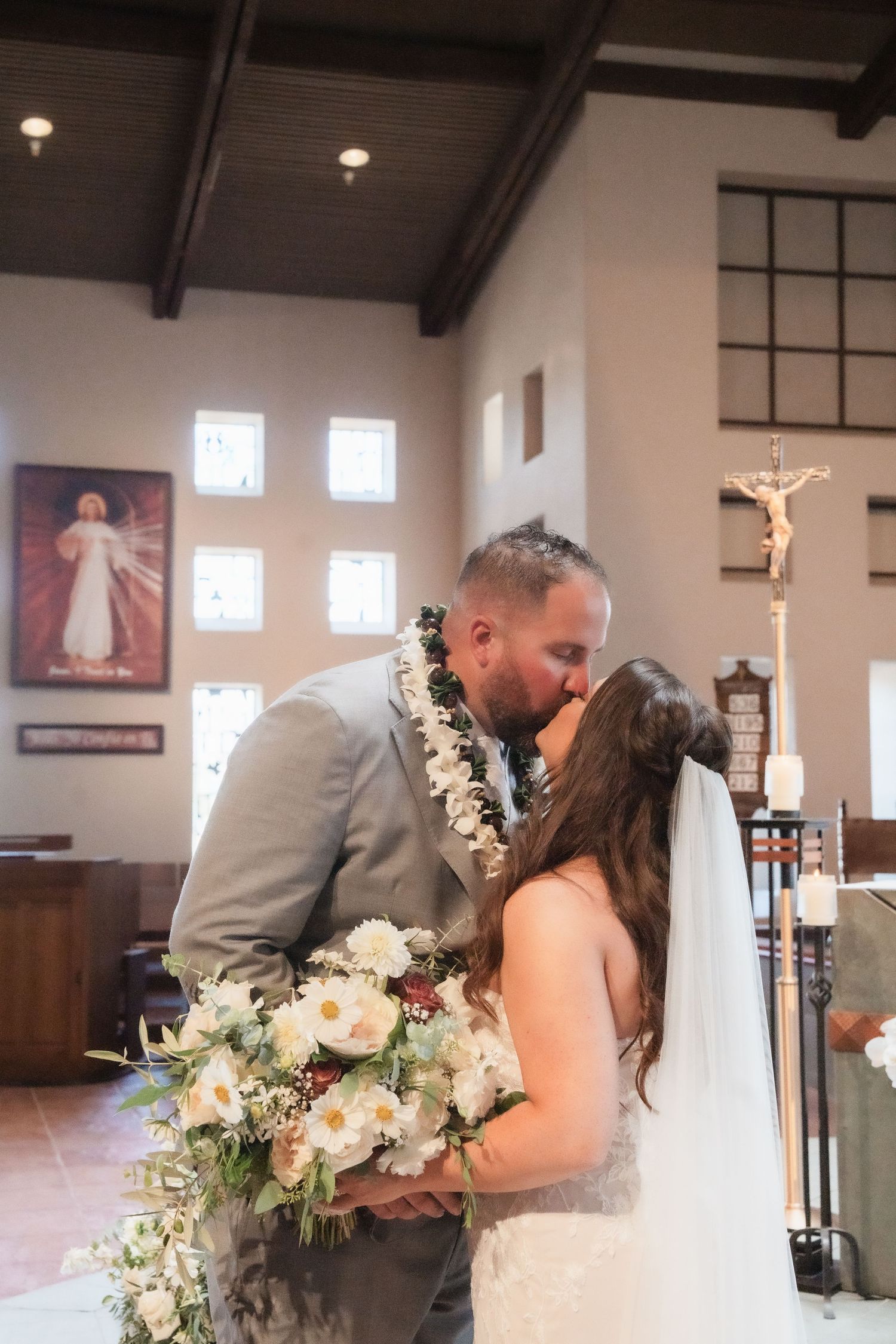 Wedding ceremony moment in church sanctuary with dark wood beams and religious artwork.