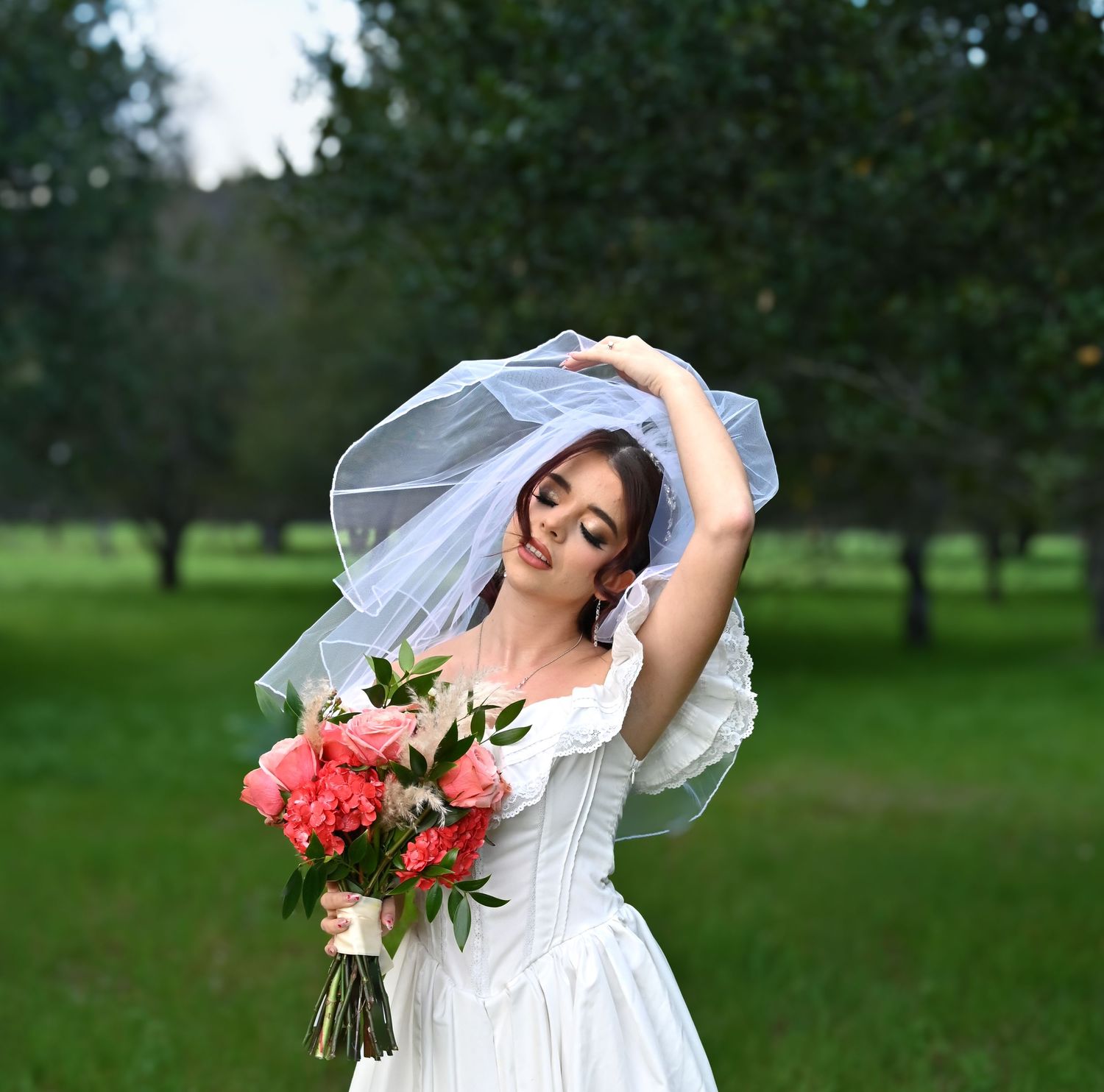 Artistic bridal portrait series featuring flowing white dress and coral bouquet in outdoor setting.