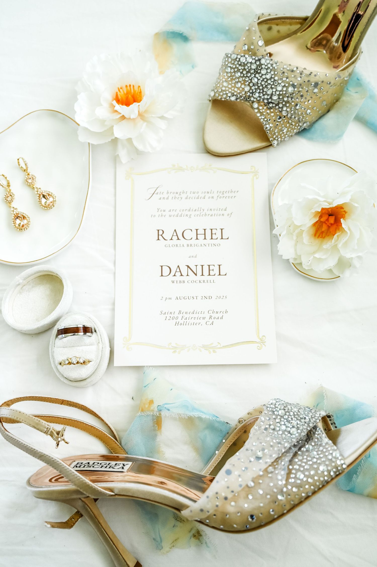 Wedding details including sparkly shoes, invitations and delicate jewelry on white surface.