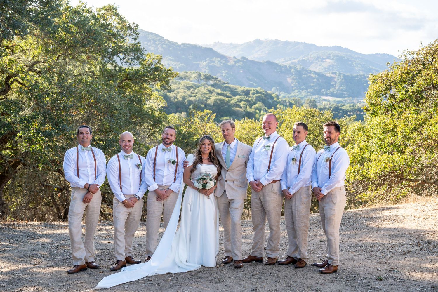Carmel Valley Wedding, California  Wedding party in white and khaki poses against scenic mountain backdrop in outdoor summer setting.