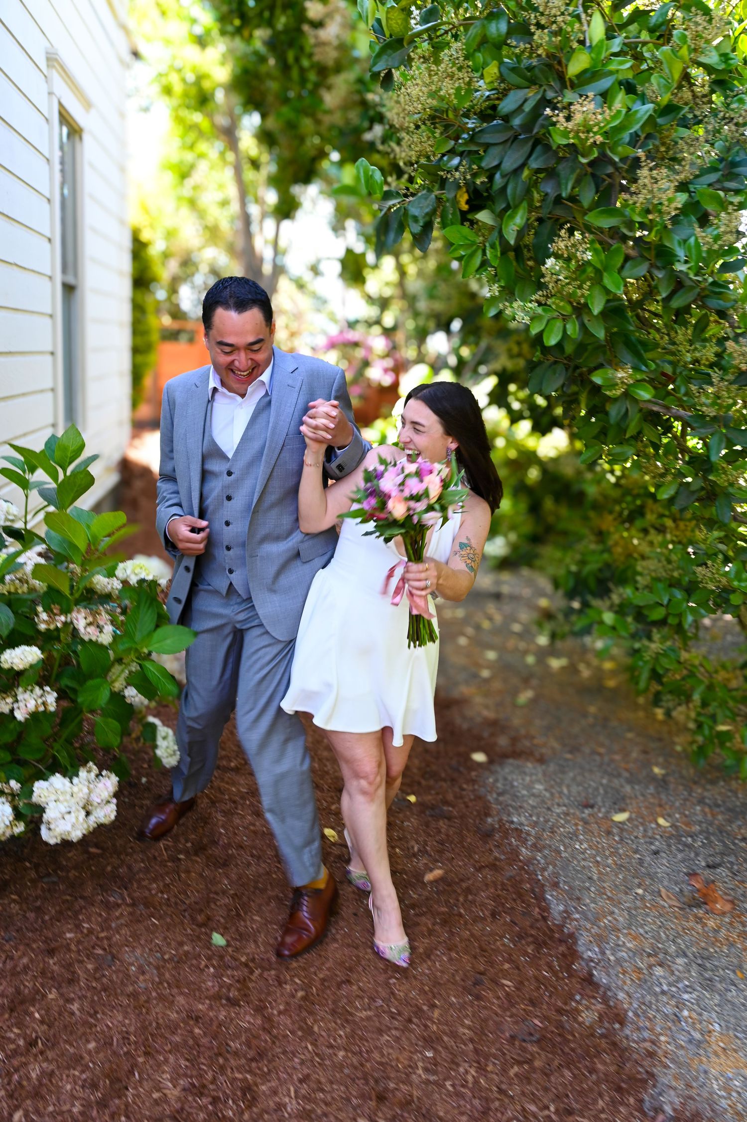 Two people sharing a playful moment on a mulch-covered garden path.
