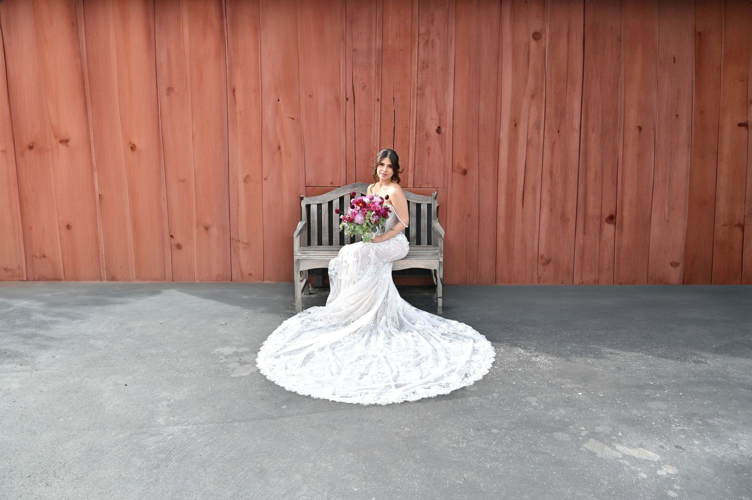 A minimalist view of a white wedding dress train against a rustic wooden floor.