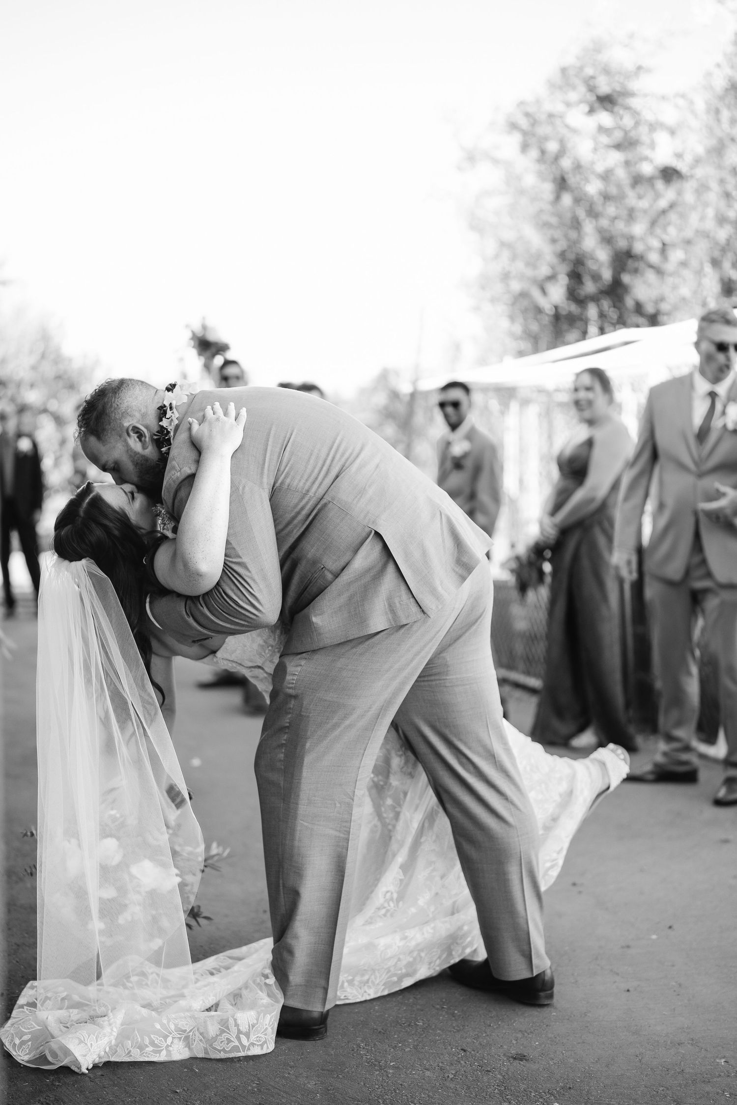Black and white photo of a romantic dip pose during an outdoor wedding.