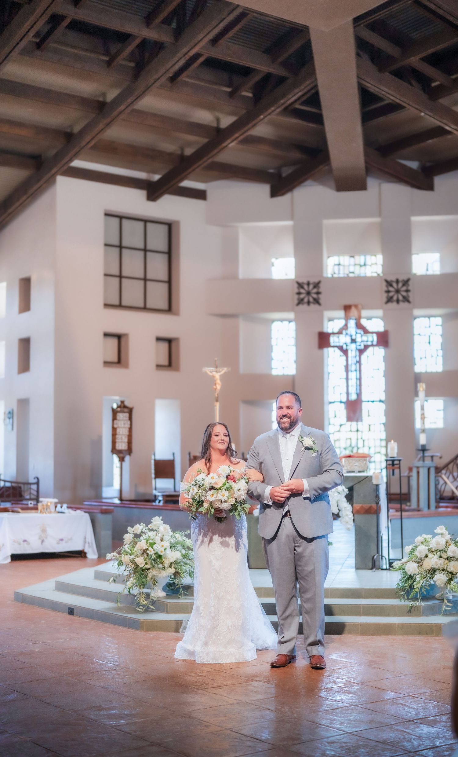 First look moment in a church sanctuary with exposed wooden beams and stained glass windows.