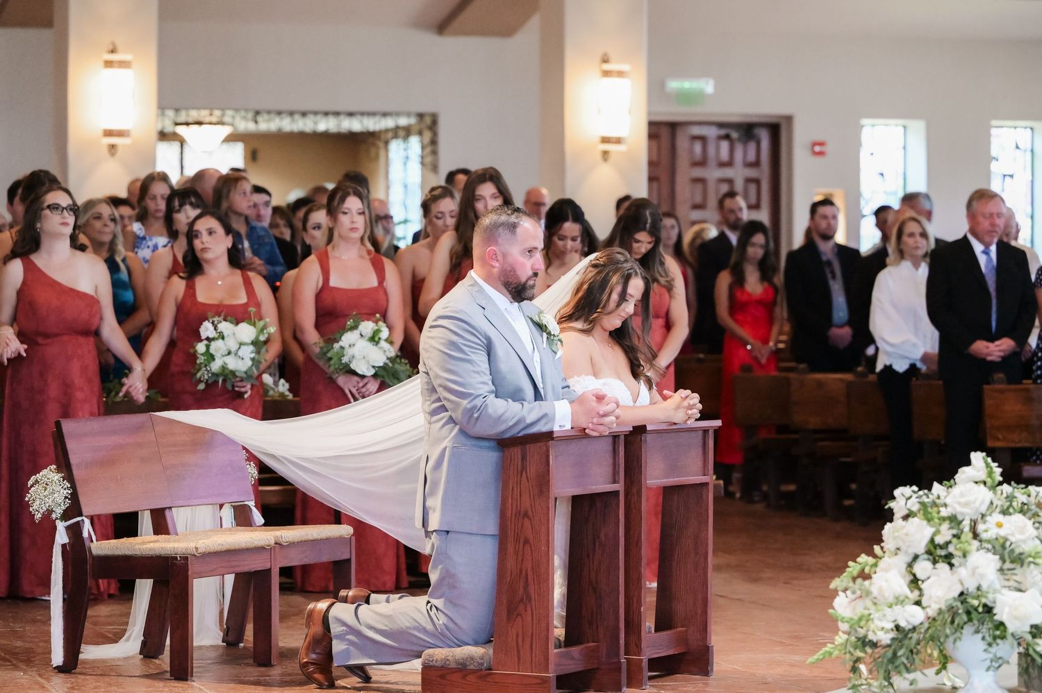 Wedding ceremony in a traditional church sanctuary with guests seated in wooden pews.