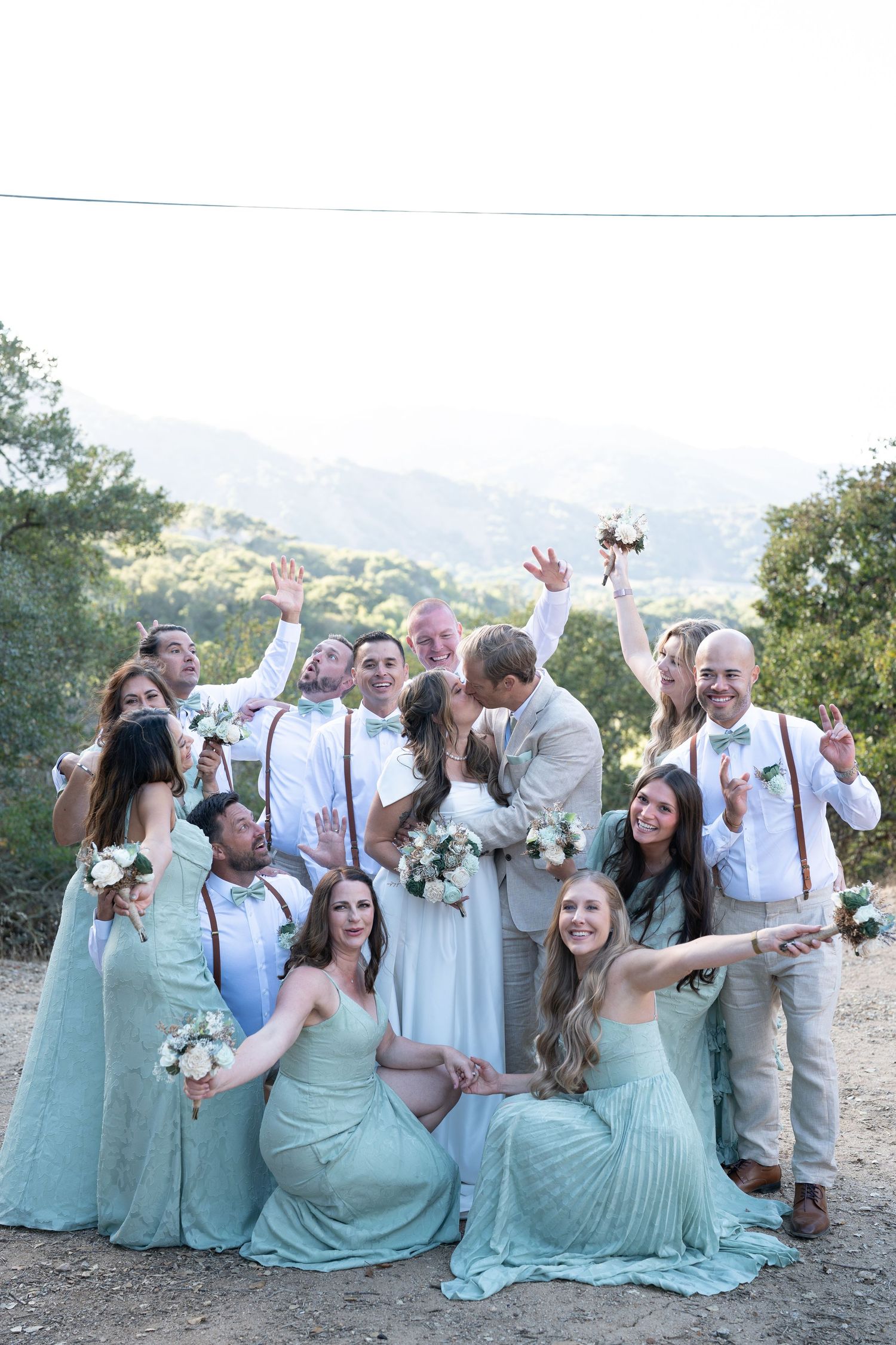 Carmel Valley Wedding, California Wedding party in mint green dresses poses playfully for candid photos against a scenic mountain backdrop.