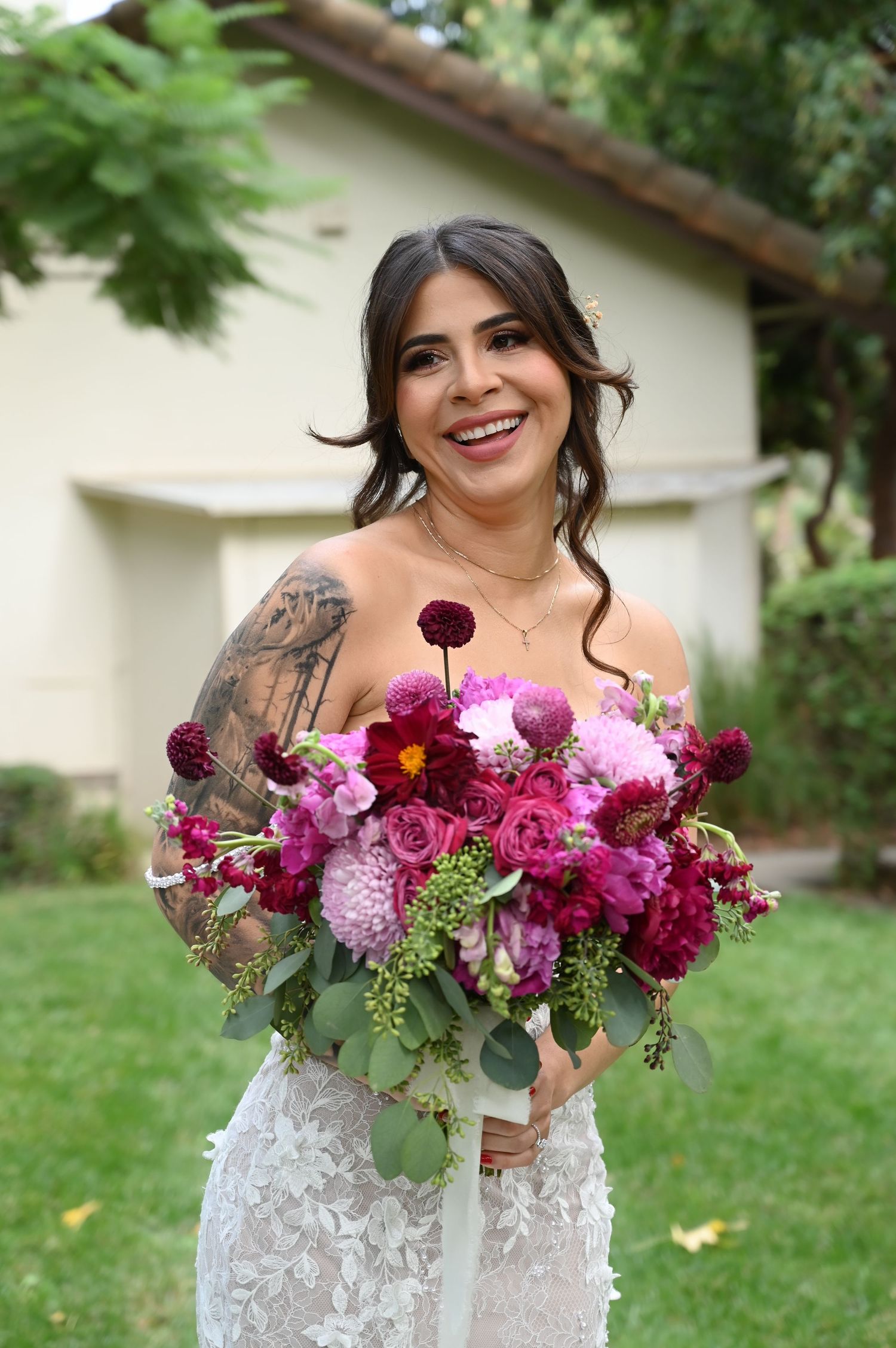 A radiant bridal moment captured with a lush bouquet of pink and burgundy flowers in an outdoor setting.