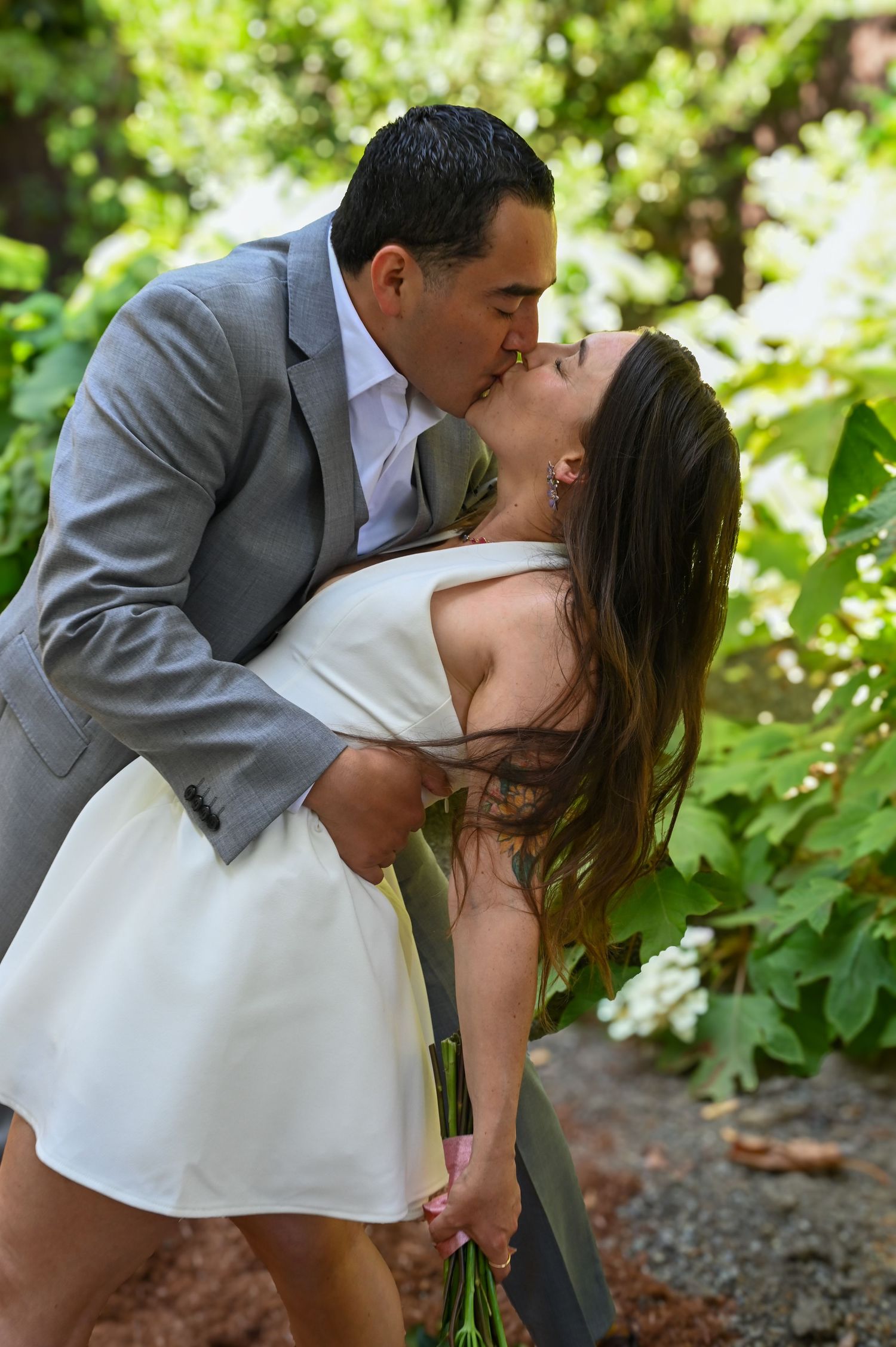 A romantic moment shared between a couple in formal attire in a garden setting.