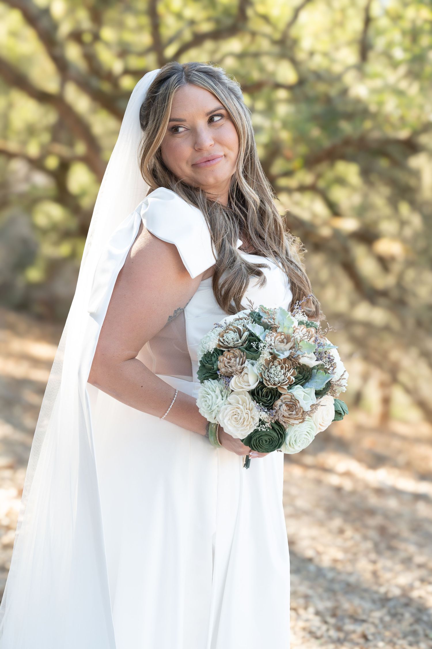 Bridal portraits with flowing white veil and elegant bouquet in natural outdoor setting.