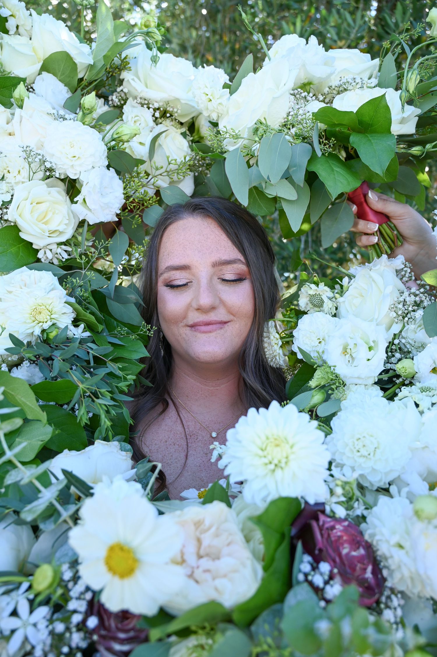 White floral arrangement with roses and greenery in a garden setting.