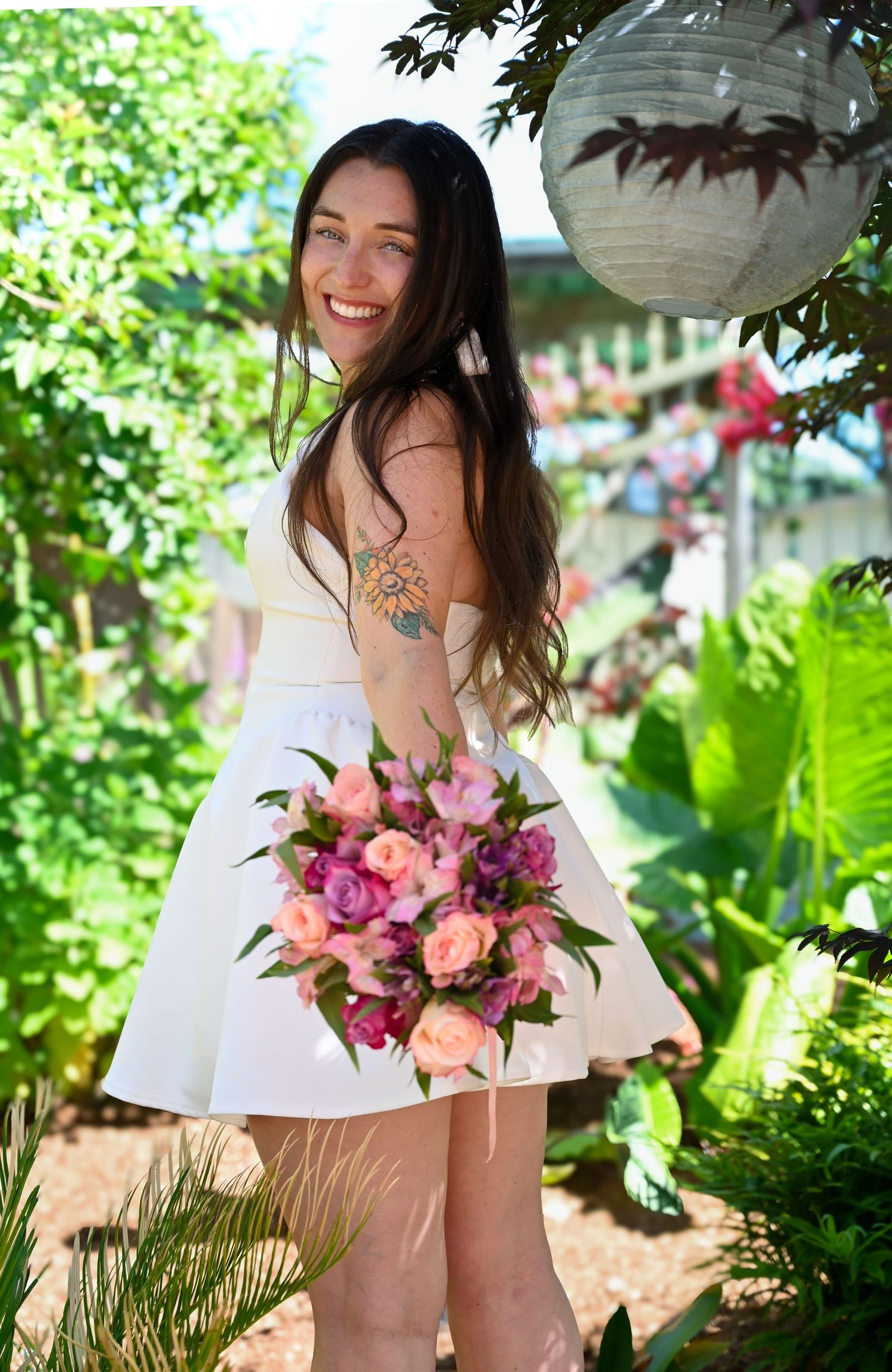 A beautiful bouquet of pink and coral flowers held against a lush green garden background.