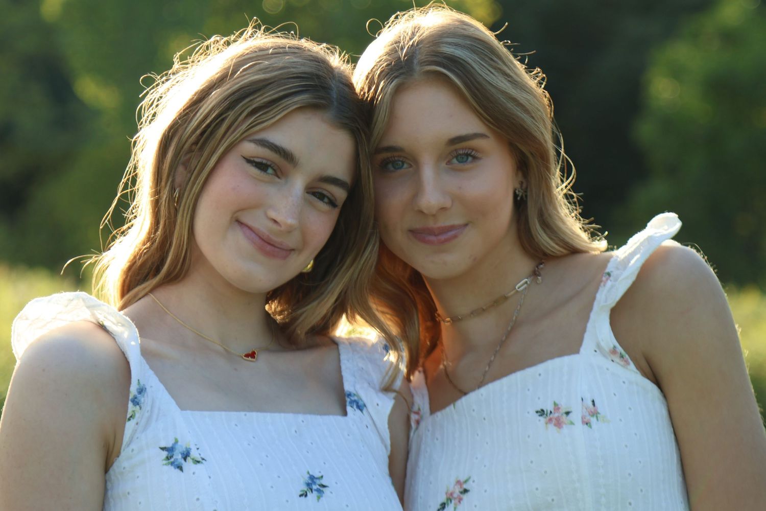 two female gently smiling in the warm sunlight while their heads are close together