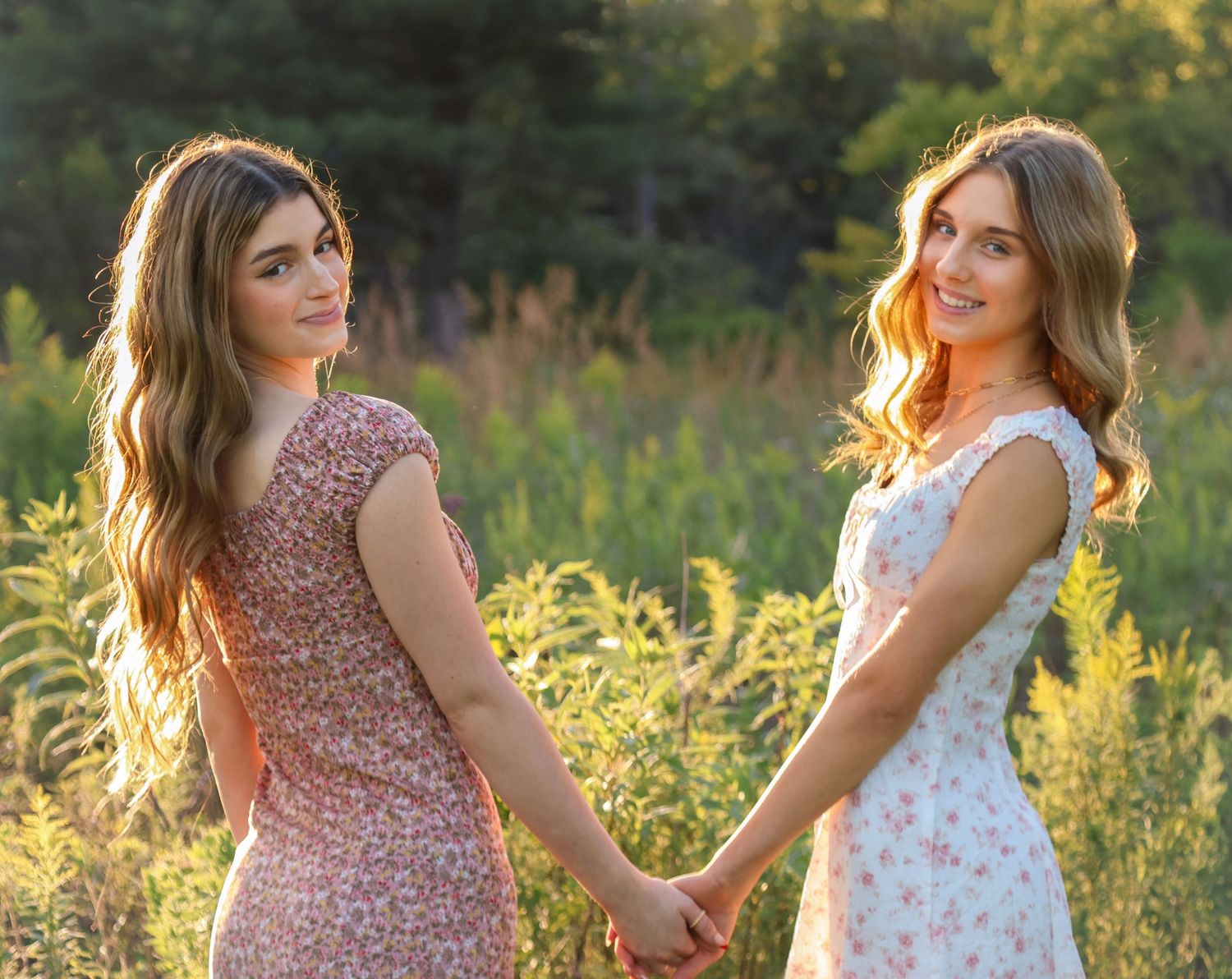 two female seniors holding hands in the warm sunlight and looking back and smiling