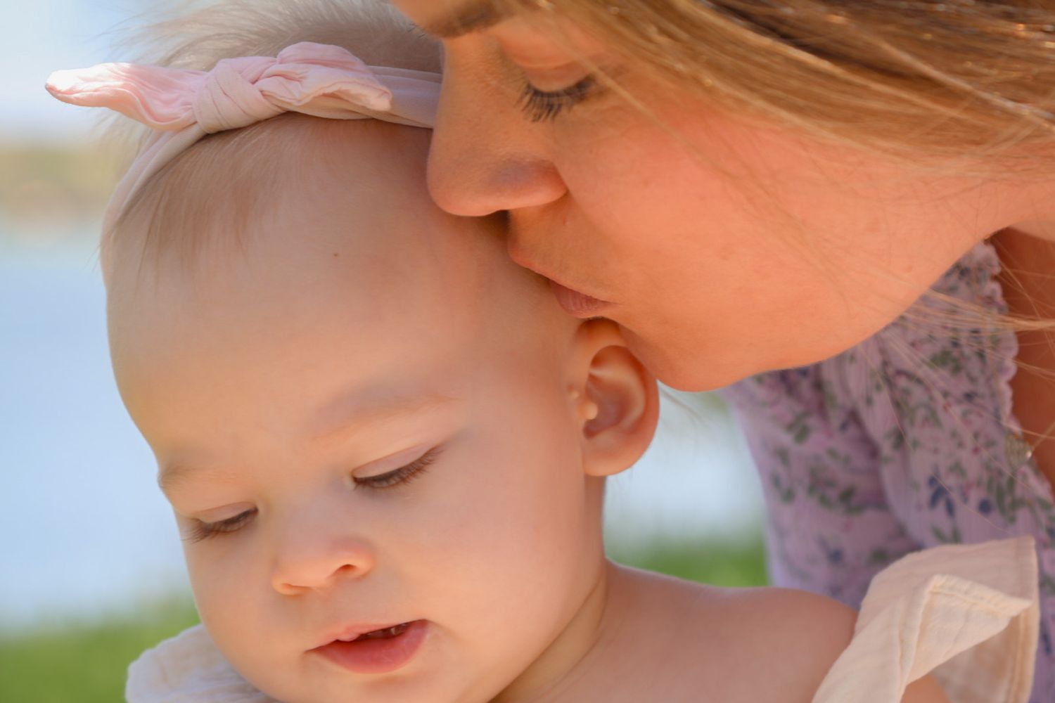 Close up of mother kissing baby daughters face in the sun in Cedar Lake In