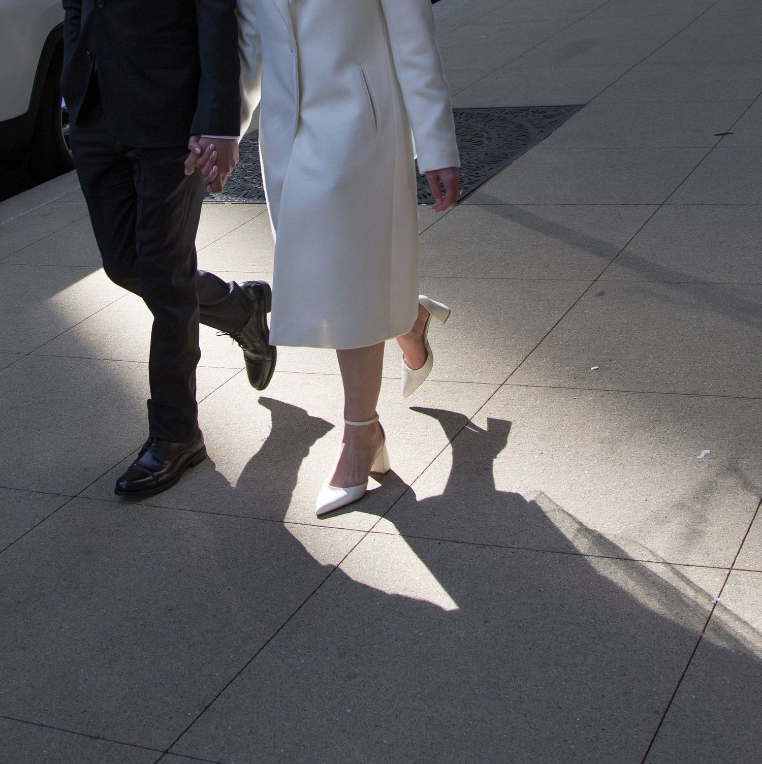 Bride and Groom walk on Chicago streets as sun casts shadows, artsy cropped photo of only their lower halves