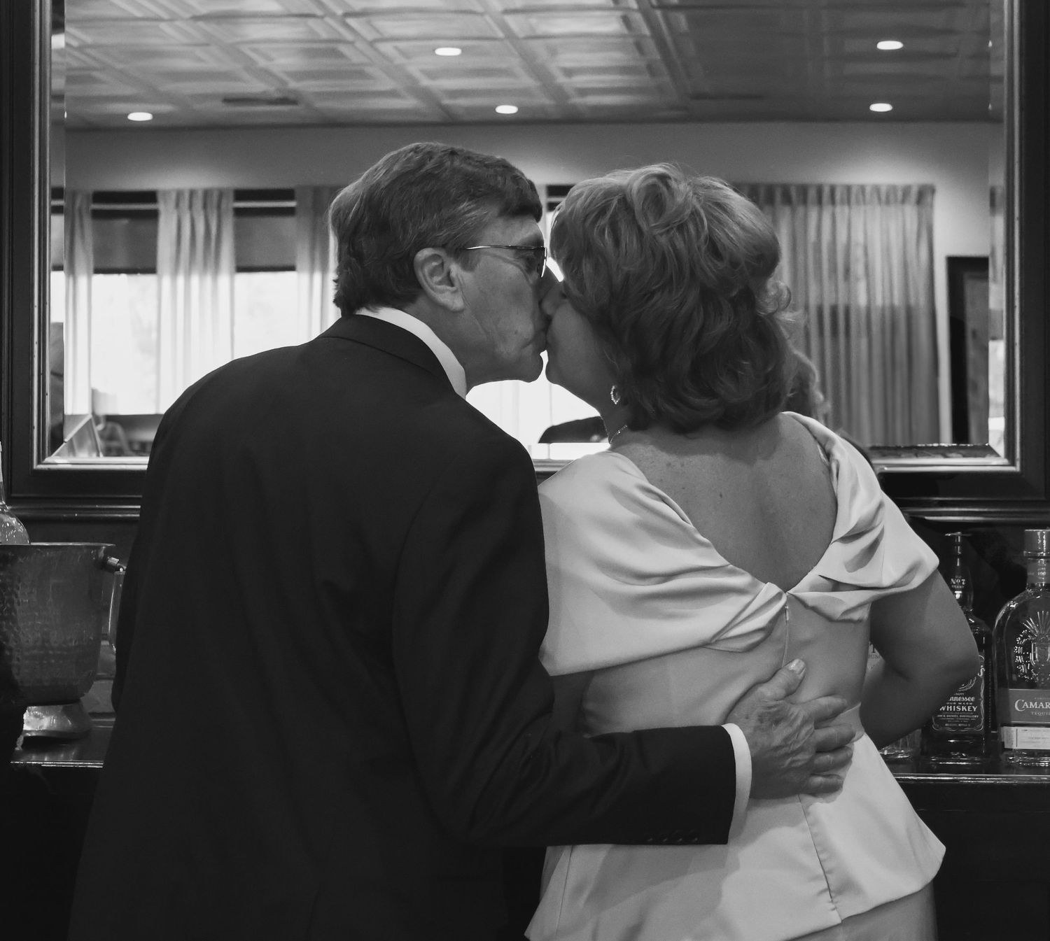 Groom kisses bride at the bar at their wedding, photo is black and white