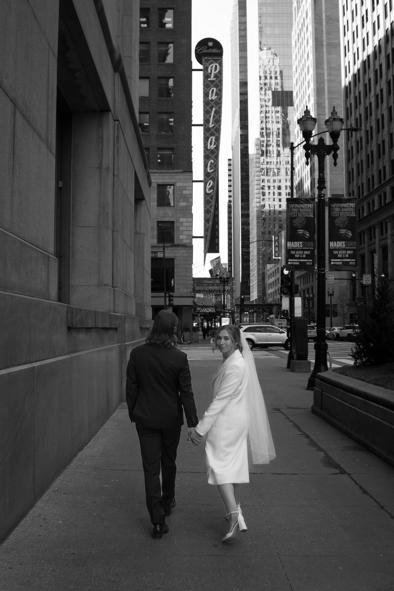 Bride and groom walk down chicago streets. bride playfully glances back at camera.