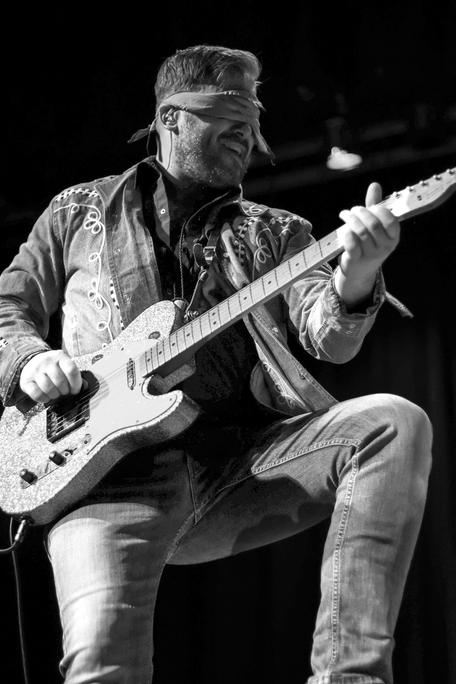 Lead singer of the band Iron Horse has a bandana covering his eyes as he plays his guitar