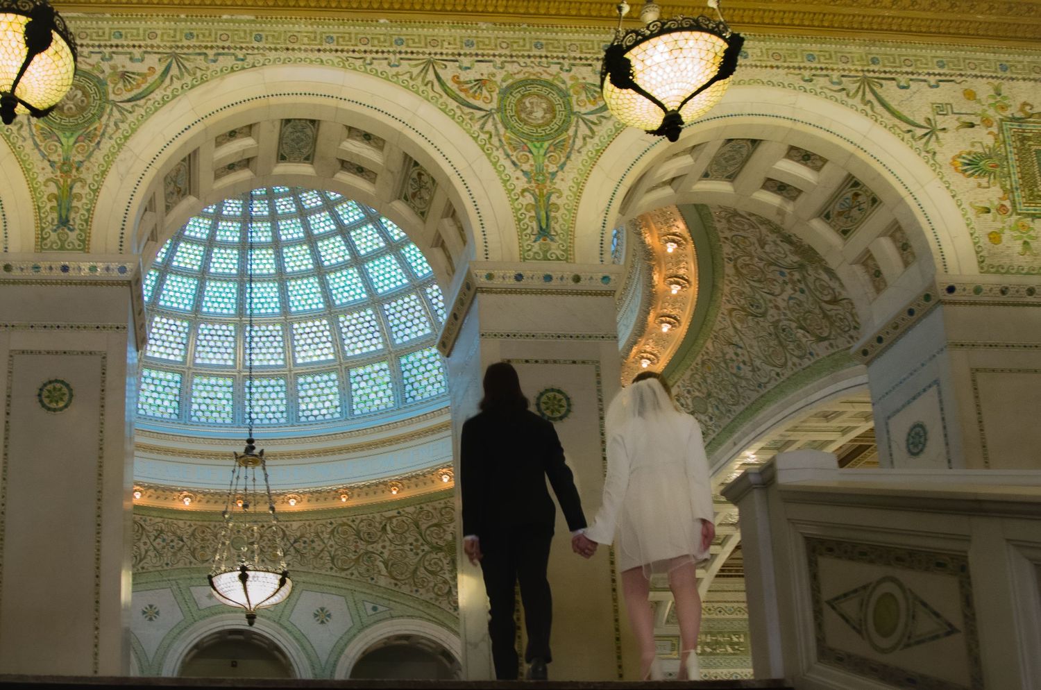 Bride and Groom look in awe at the Chicago Cultural center dome ceiling and all the decorative design of the building
