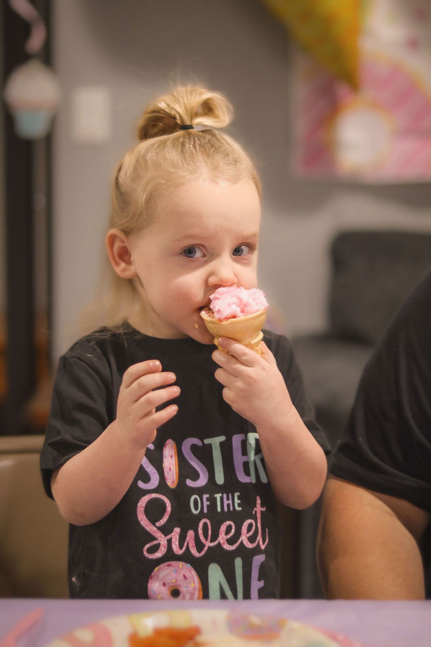Big sister eats cotton candy cone at birthday party for little sister