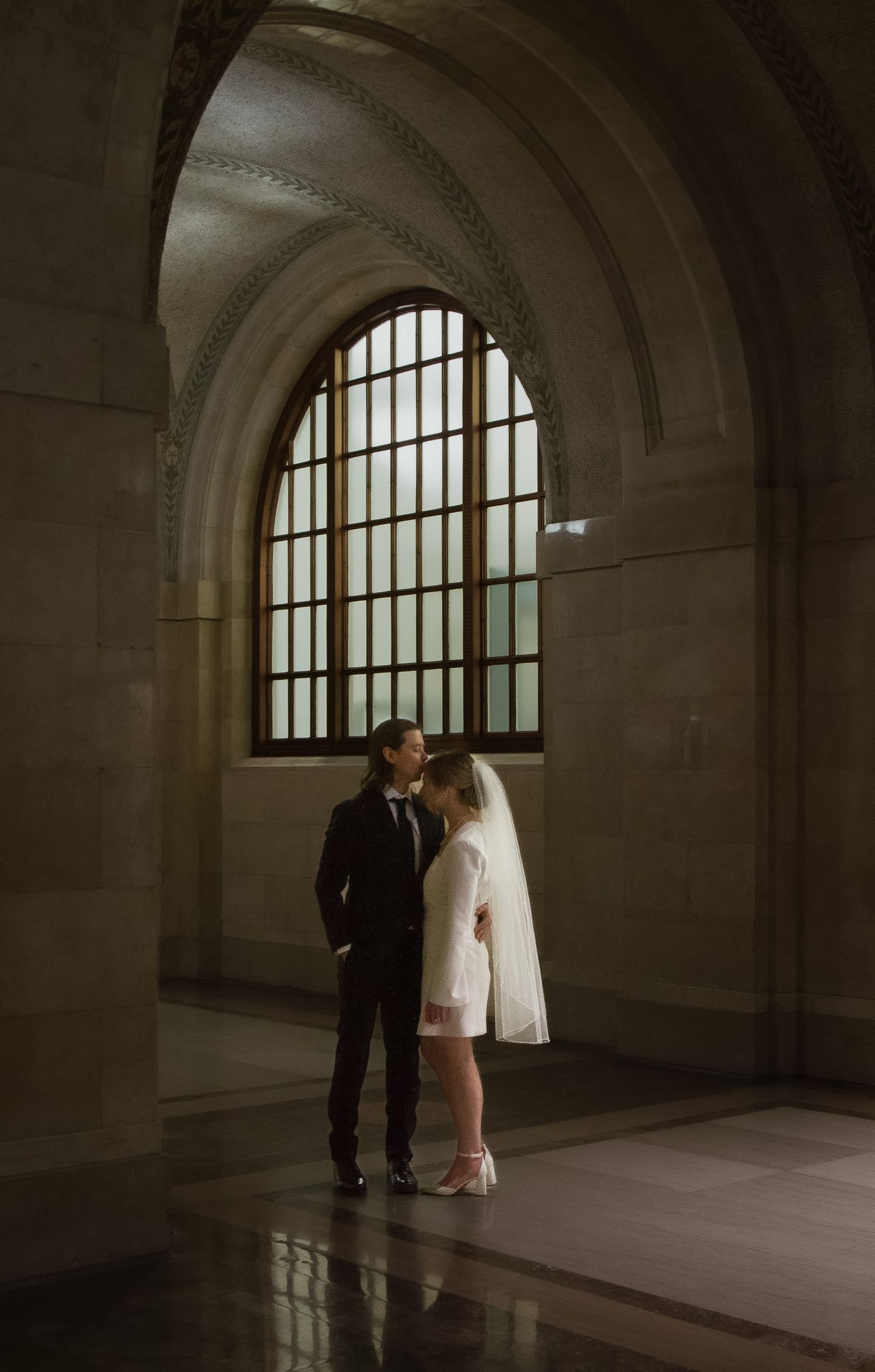 Groom gently kisses forehead of the bride in the beautiful architecture of the  Chicago Courthouse right before their elopement