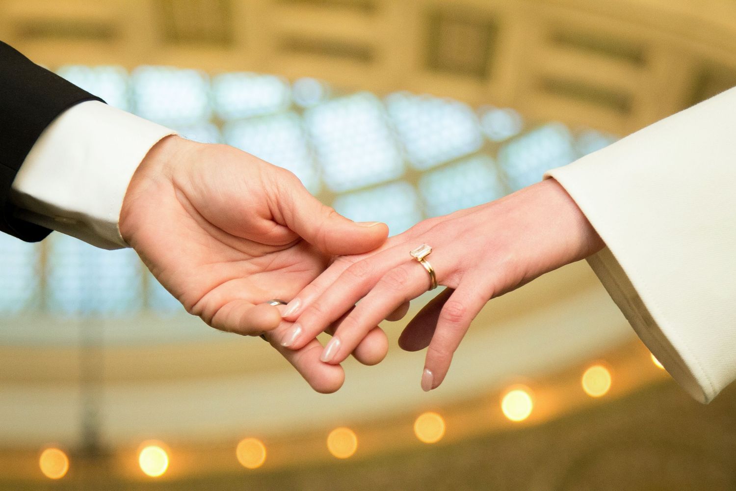 Groom and Brides hands delicately touching in Chicago Cultural Center while brides weddings bands are shown