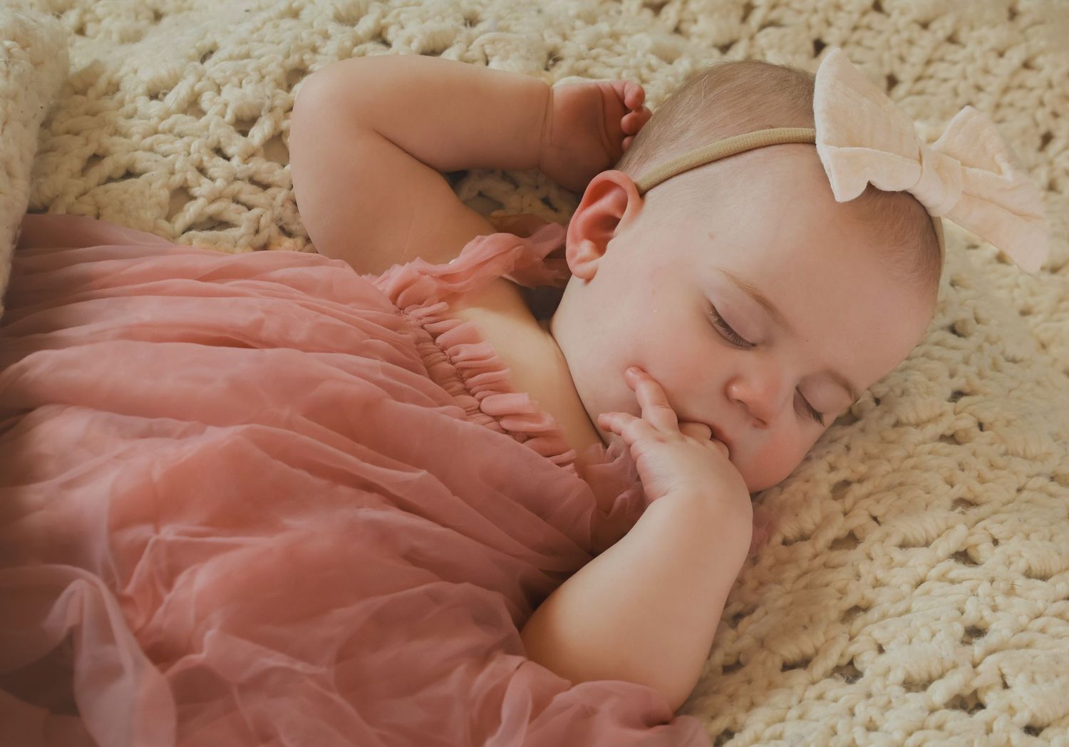 One year old girl asleep on crochet blanket in dusty tulle dress and bow photo by Kristin photo co in home session
