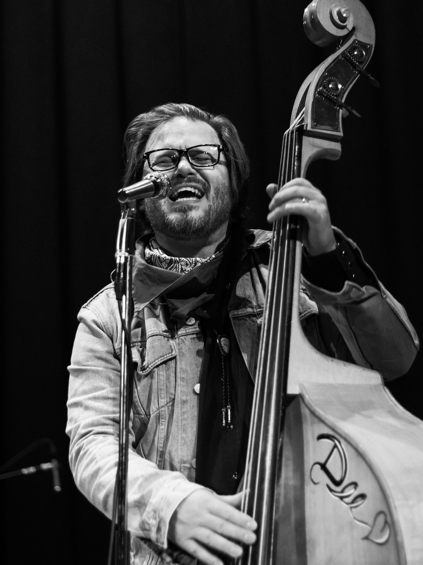 Bass player and back up singer of the band Iron Horse sings into microphone as he plays his bass