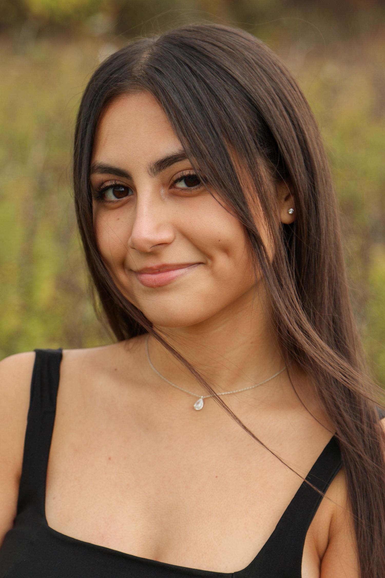 Brunette senior girl playfully smiles at camera