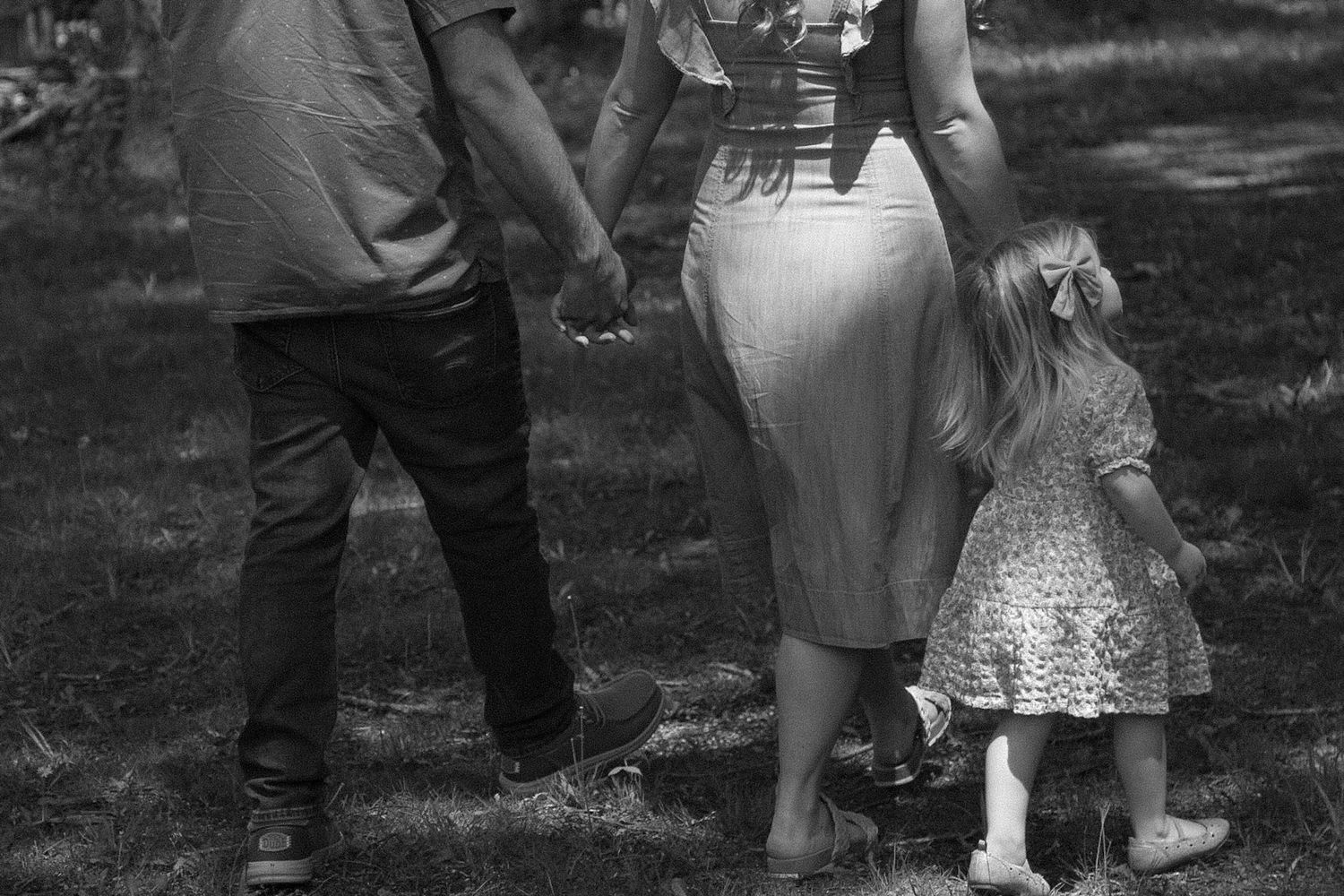 black and white cropped photo of dad mom and toddler girl walking away and holding hands photo at lemon lake indiana