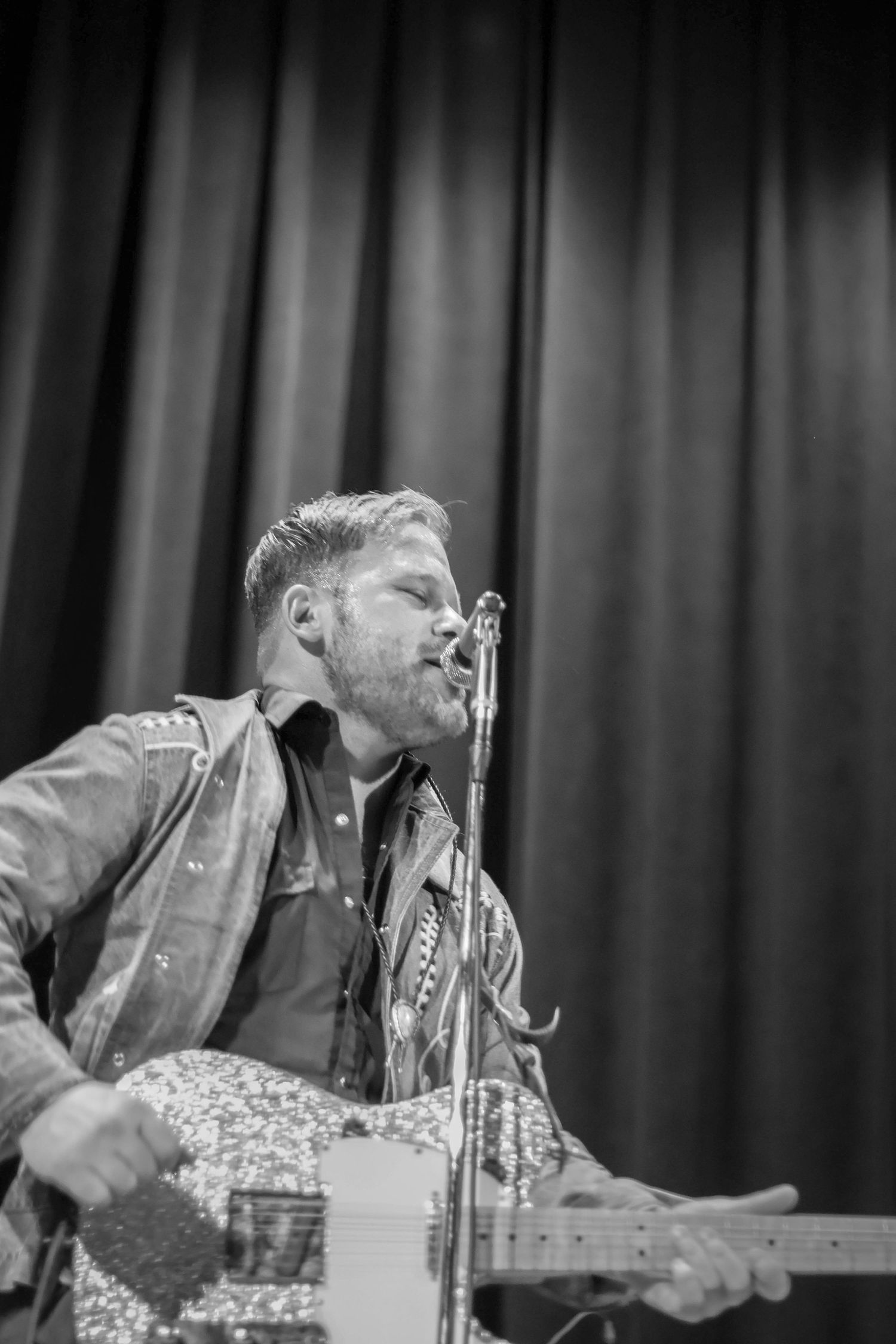 Lead singer of the band Iron Horse sings into the microphone as he plays his guitar