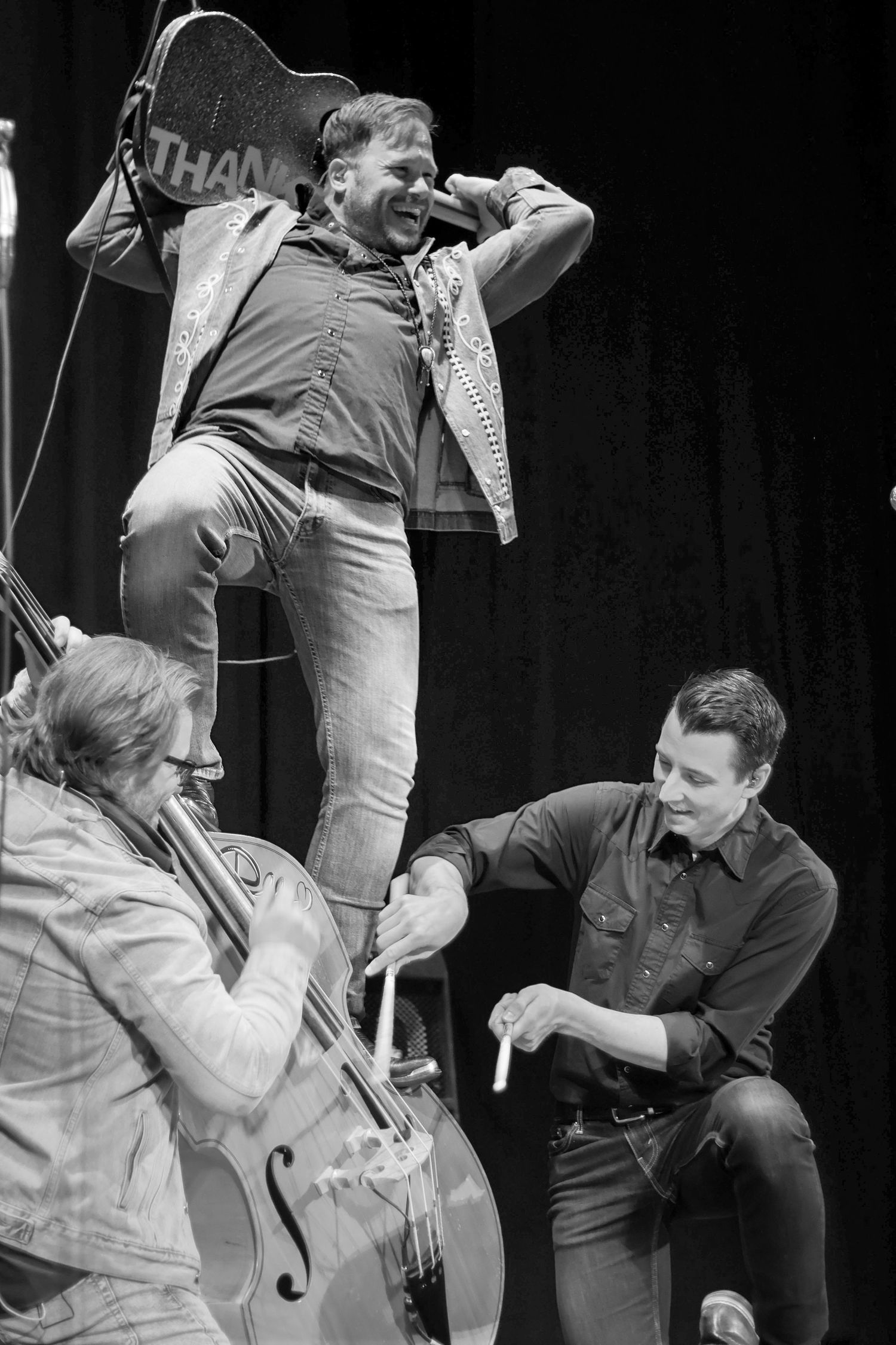 The band Iron Horse plays. The guitar player stands on the upright bass.The bass player holds the bass and plays the drummer plays the bass