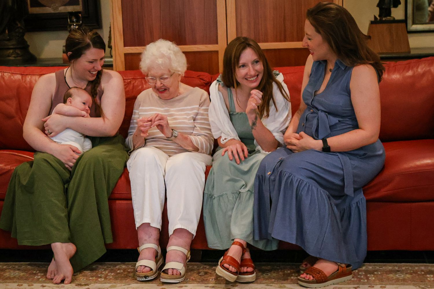 Generational photo of Grandmother with grandaughters and great grand child all laughing on a couch together