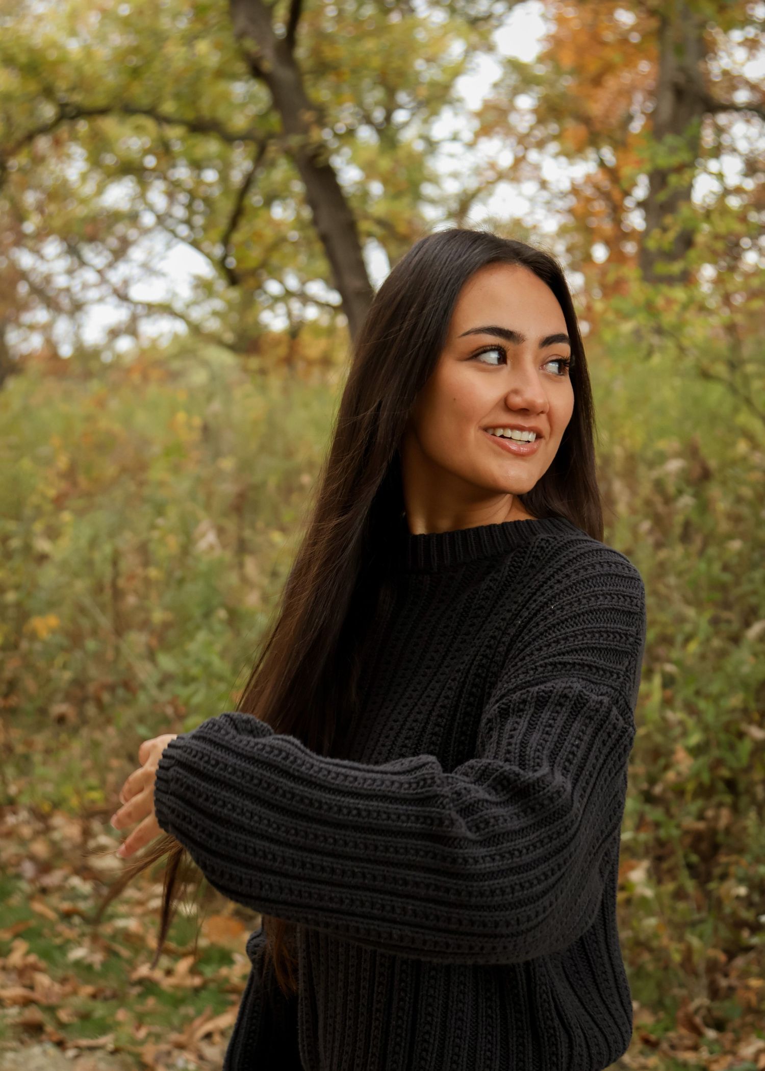 Young woman looks and as she runs her fingers thru her hair in delicate motion photo taken at Goodnow Grove Nature