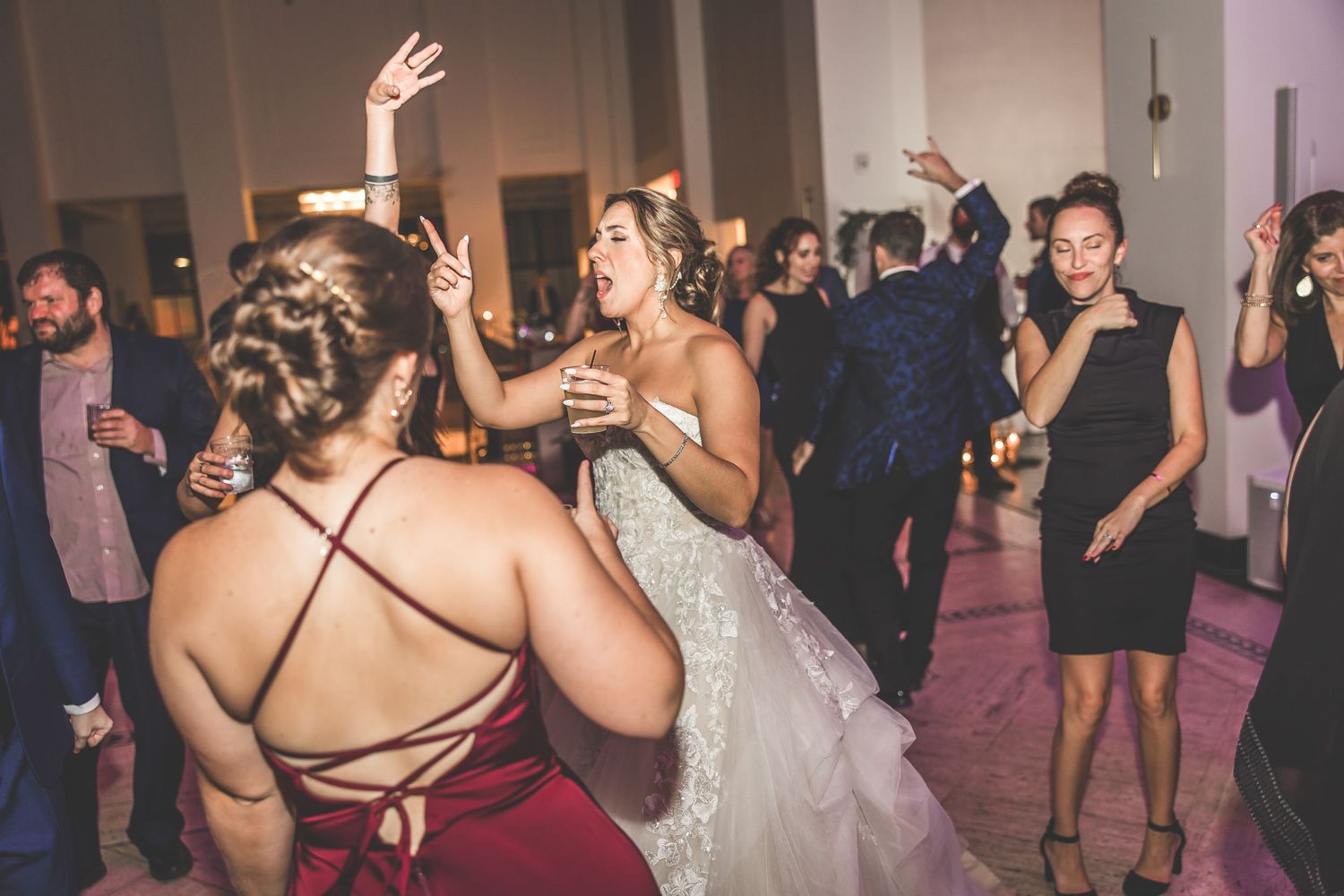 Guests dancing and celebrating at a formal wedding reception in an ornate indoor venue.