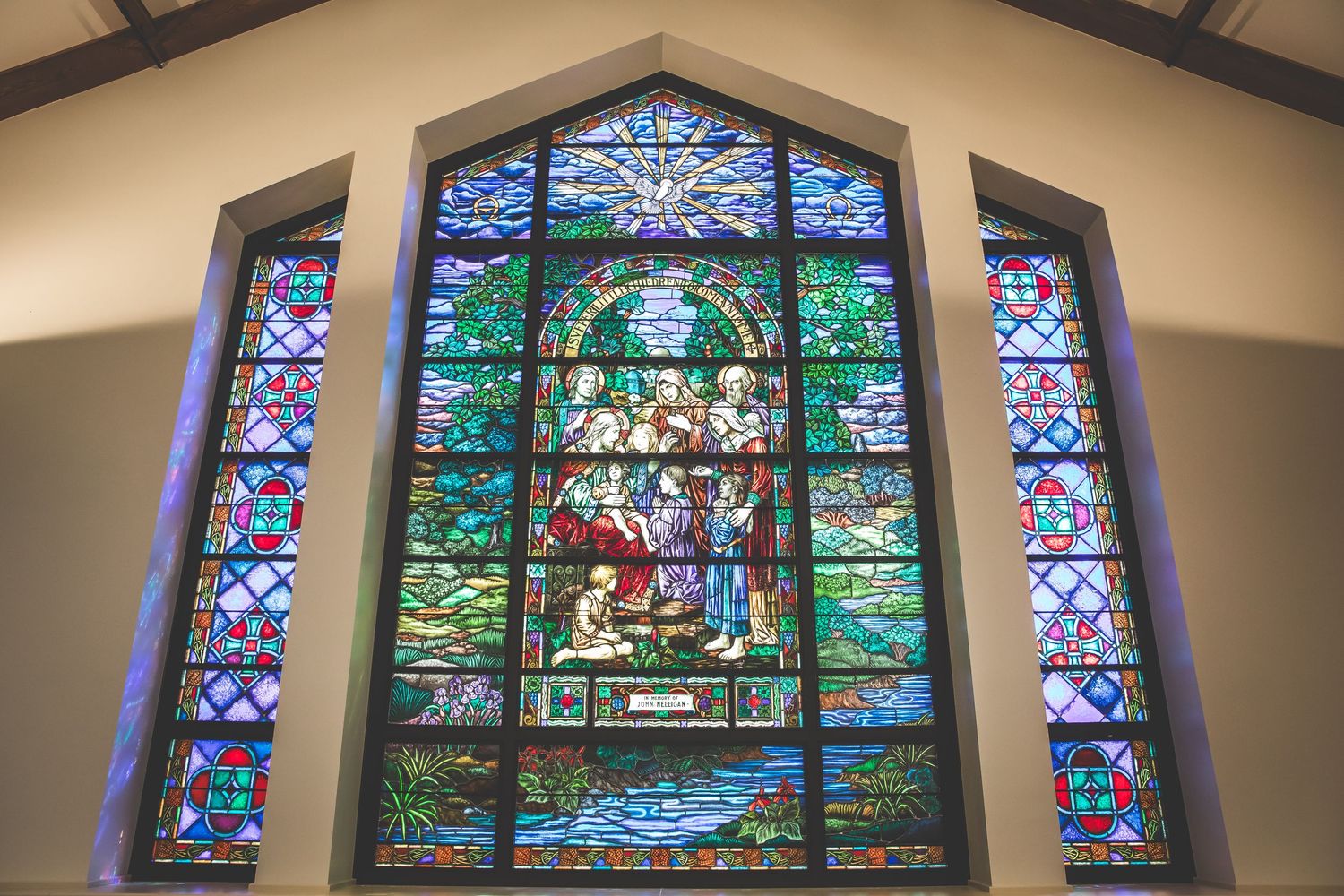 Beautiful stained glass windows with religious imagery adorn the church's upper wall.