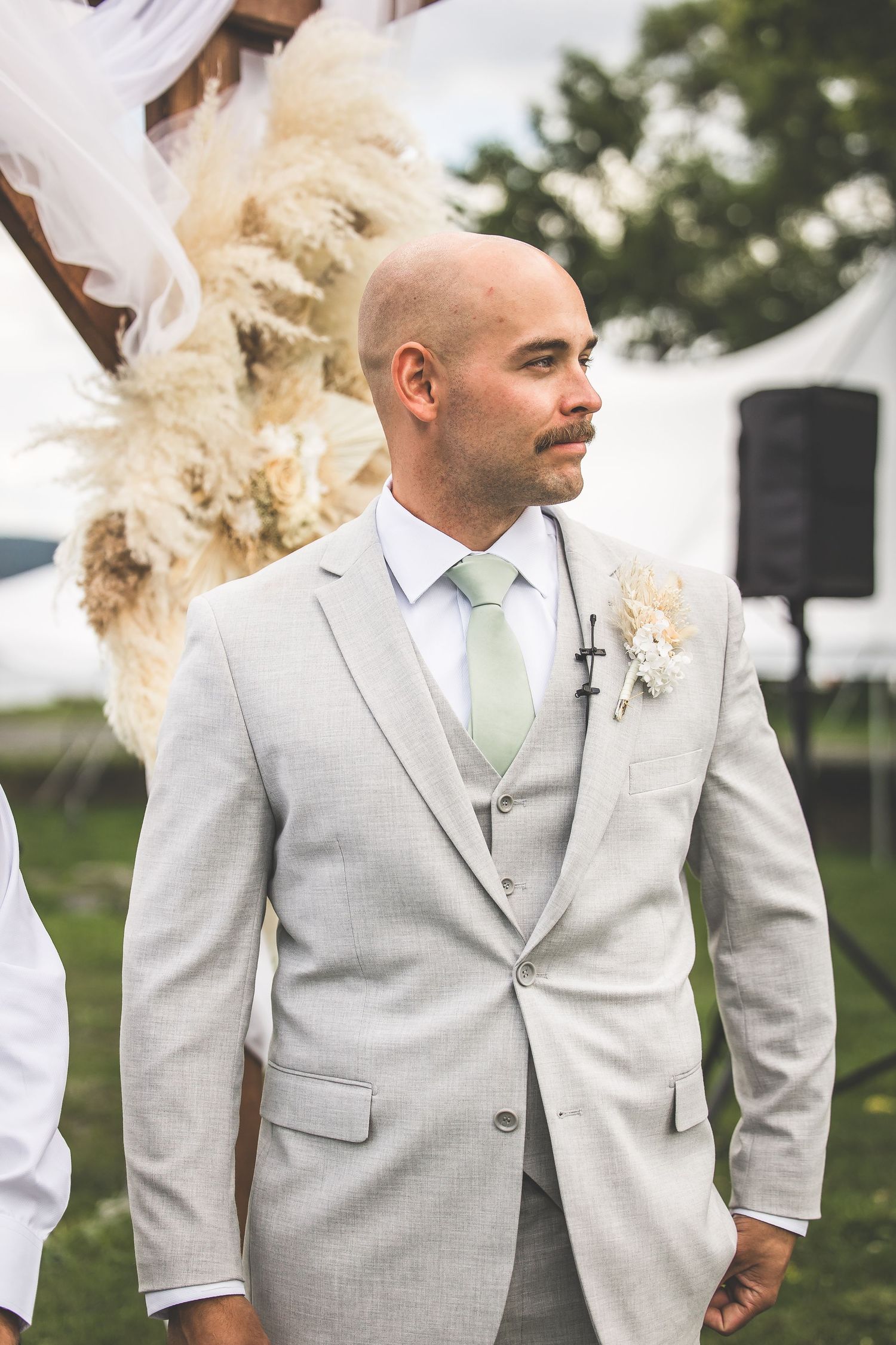 Groomsmen in light gray suits and mint green ties pose together during an outdoor wedding celebration.
