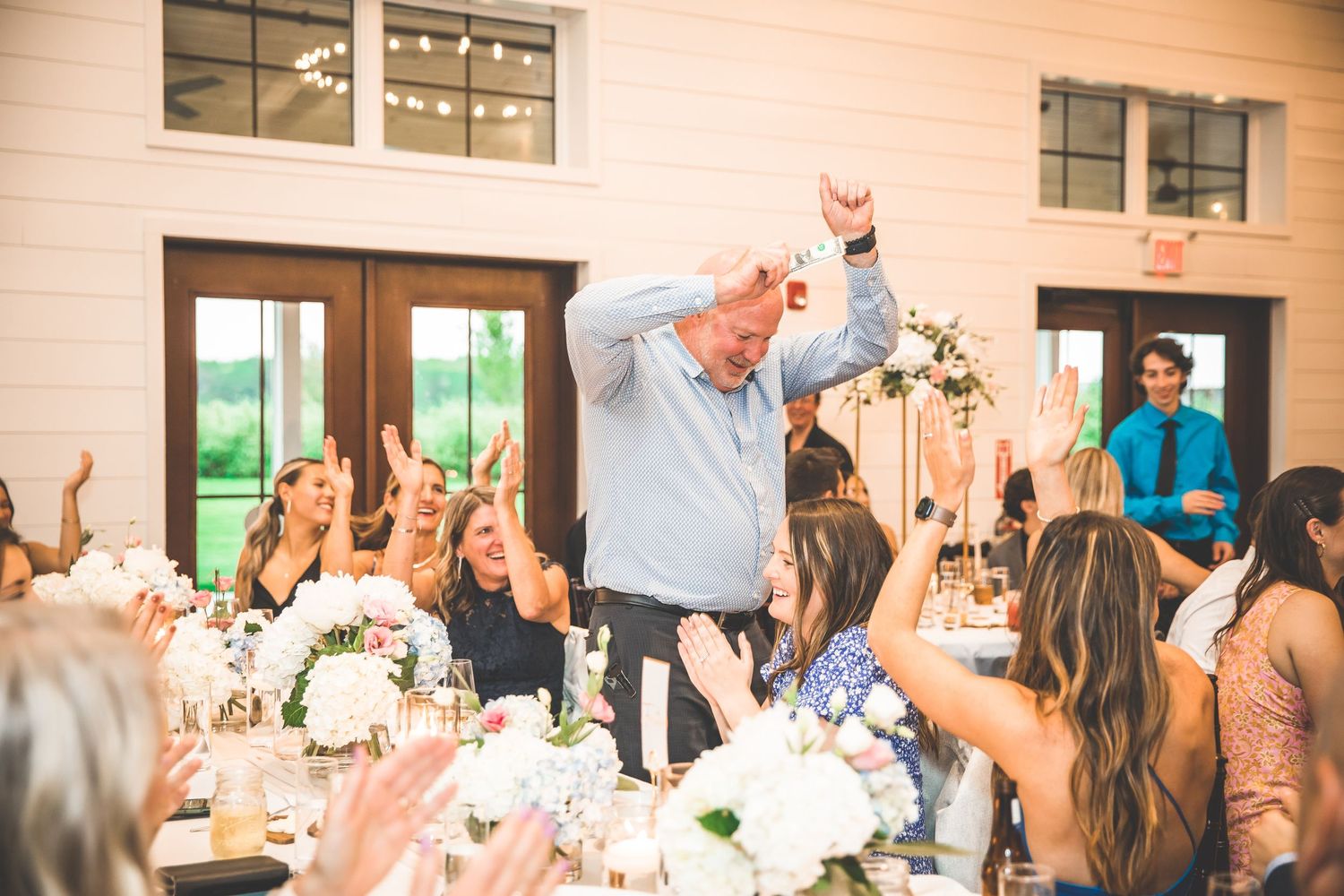 Wedding celebration with guests raising their hands in joyful celebration during reception.