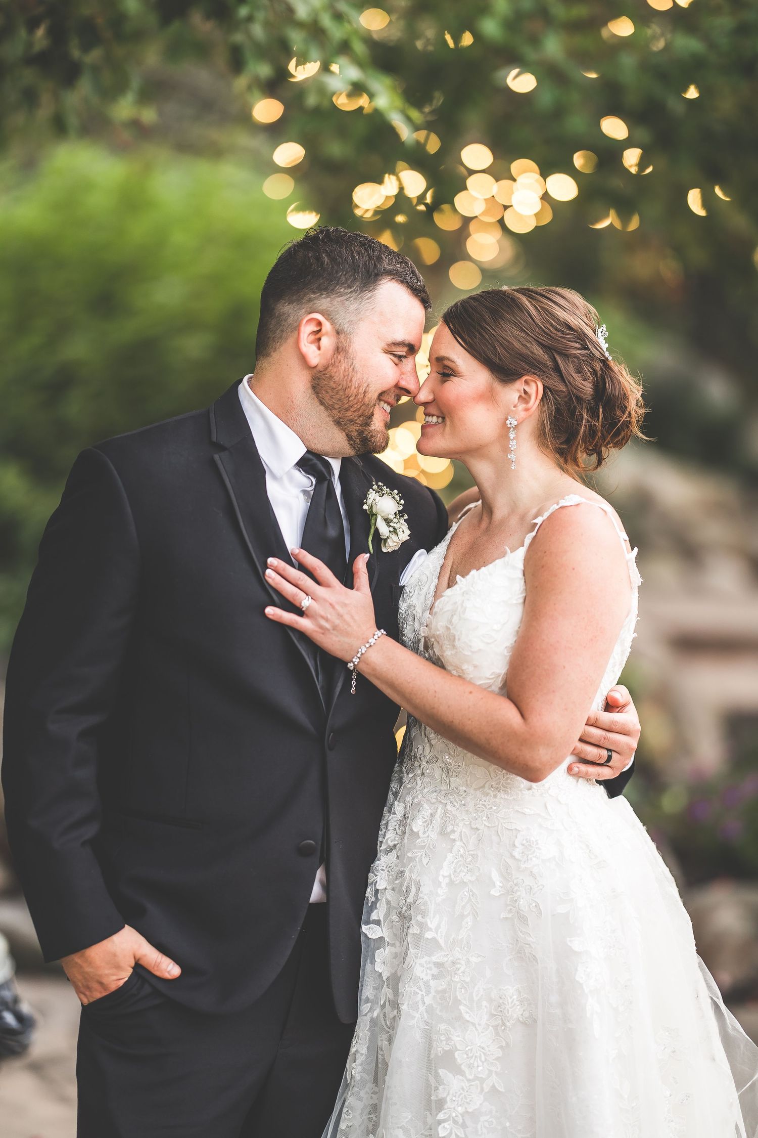 Romantic wedding couple shares intimate moments in outdoor garden setting with twinkling lights.