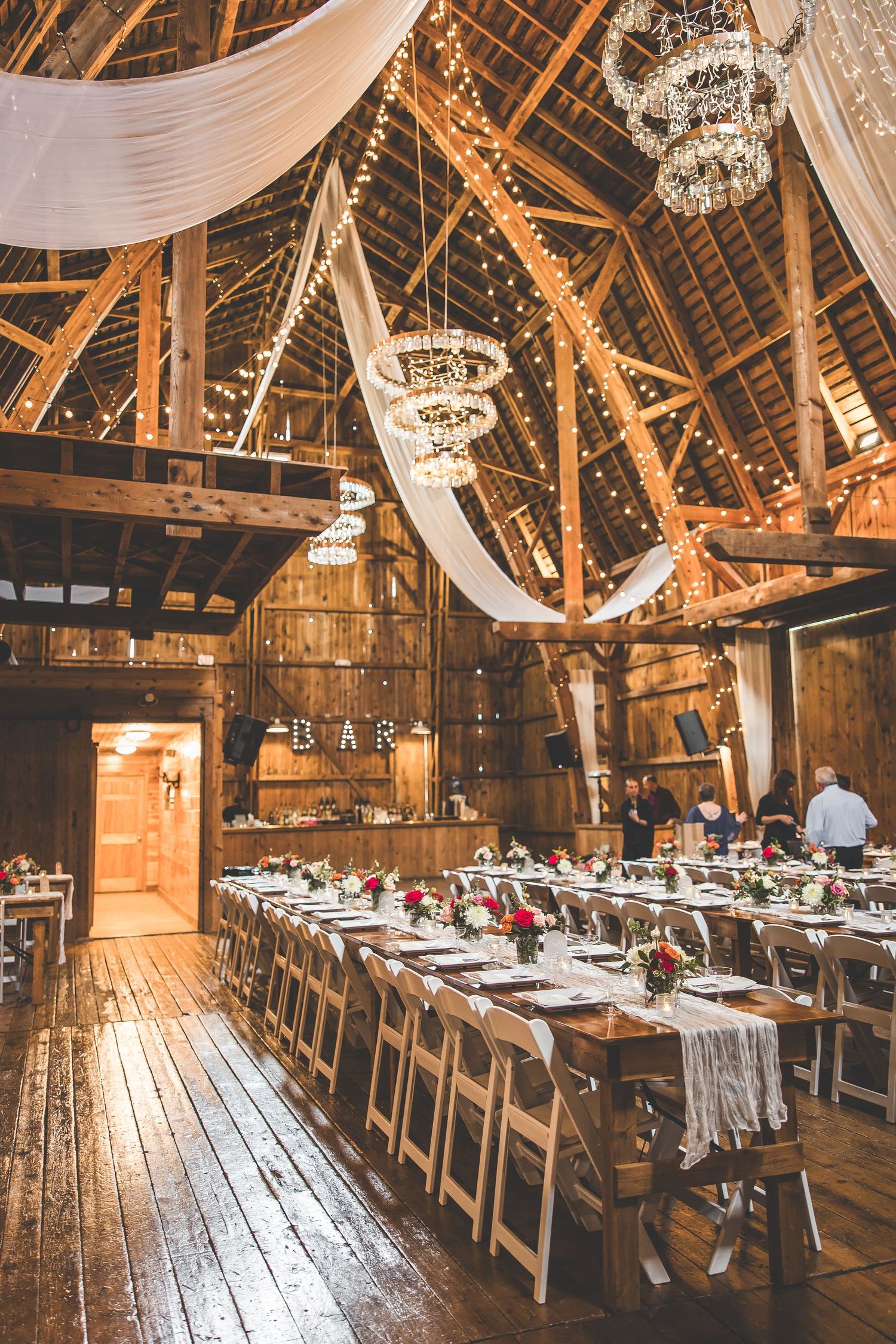 Rustic barn wedding venue with wooden benches and romantic string light decorations.